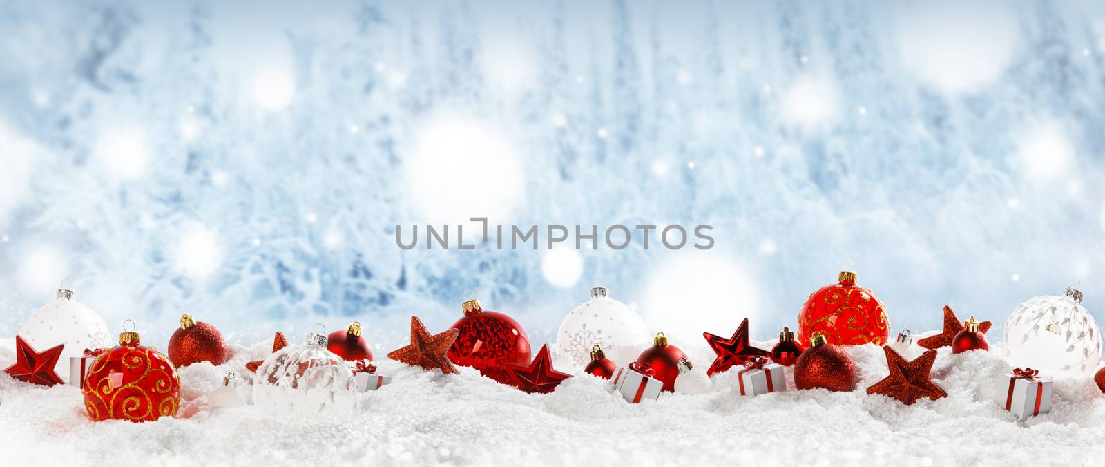 Christmas decoration frame of balls stars and gifts in snow in a row on blue winter forest bokeh background copy space for text design element