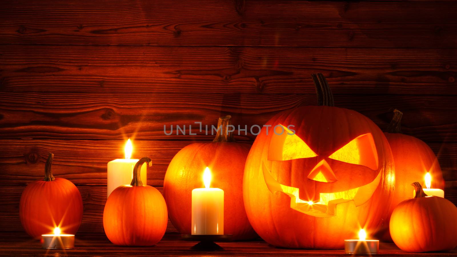Halloween pumpkin head jack o lantern and candles on wooden background