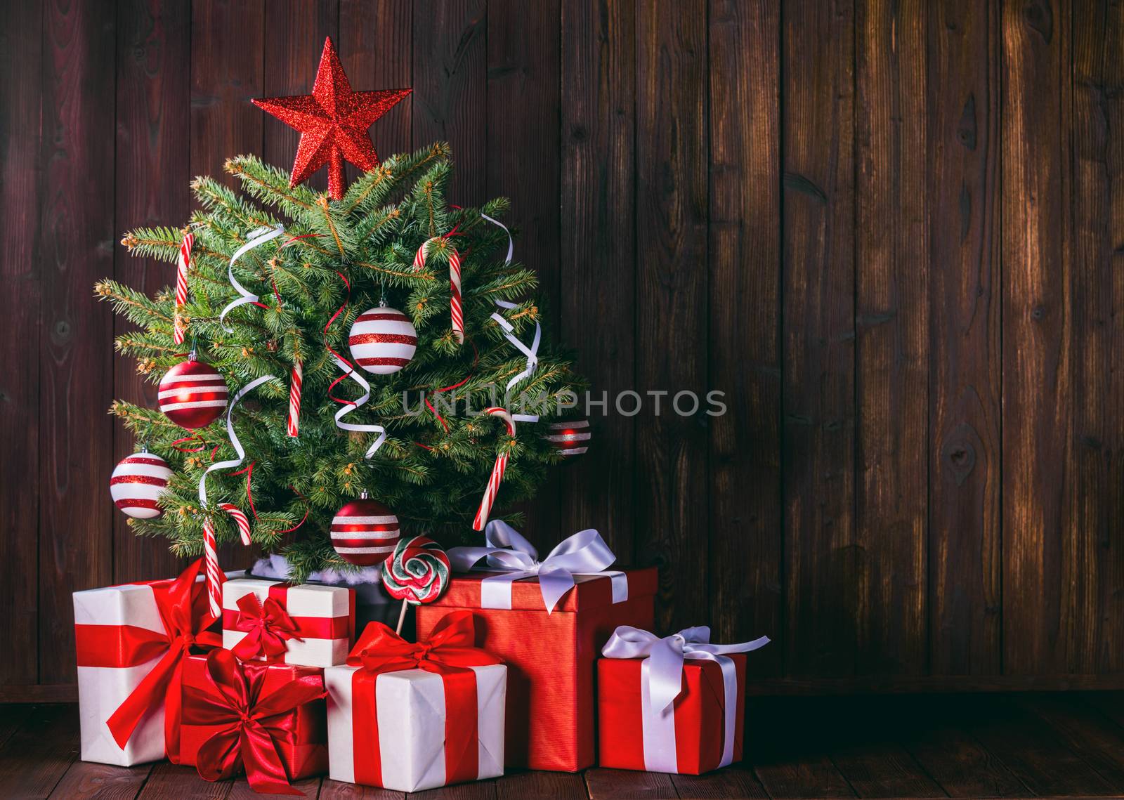 Decorated Christmas tree and gift boxes on wooden background