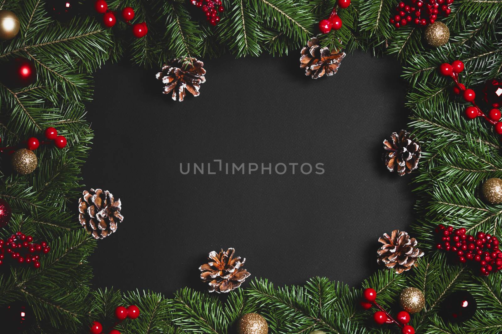 Christmas Border frame of tree branches and red berries on black paper background flat lay top view mock-up