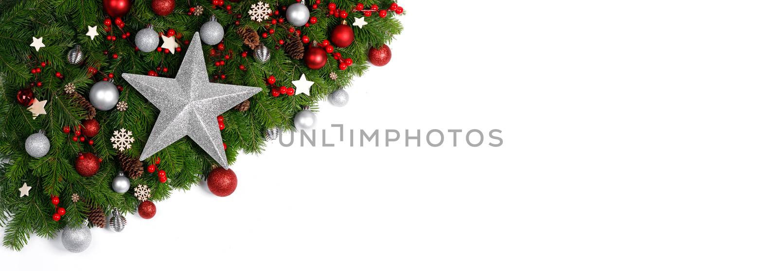 Christmas Border frame of tree branches on white background with copy space isolated, red and silver decor, berries, stars, cones