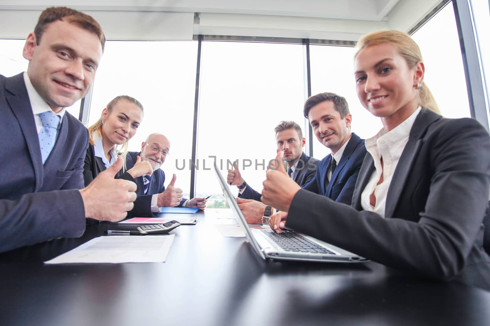 Happy business team having a meeting at office table, showing OK with thumbs up