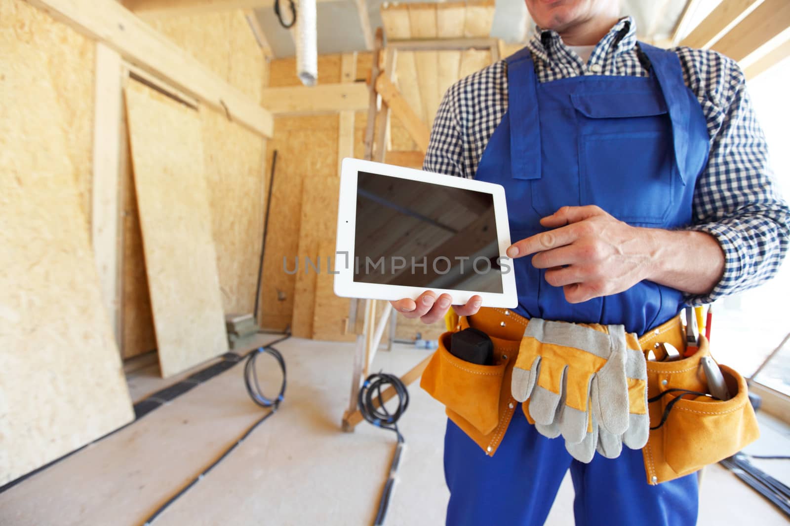 Construction worker pointing at digital tablet standing at construction site