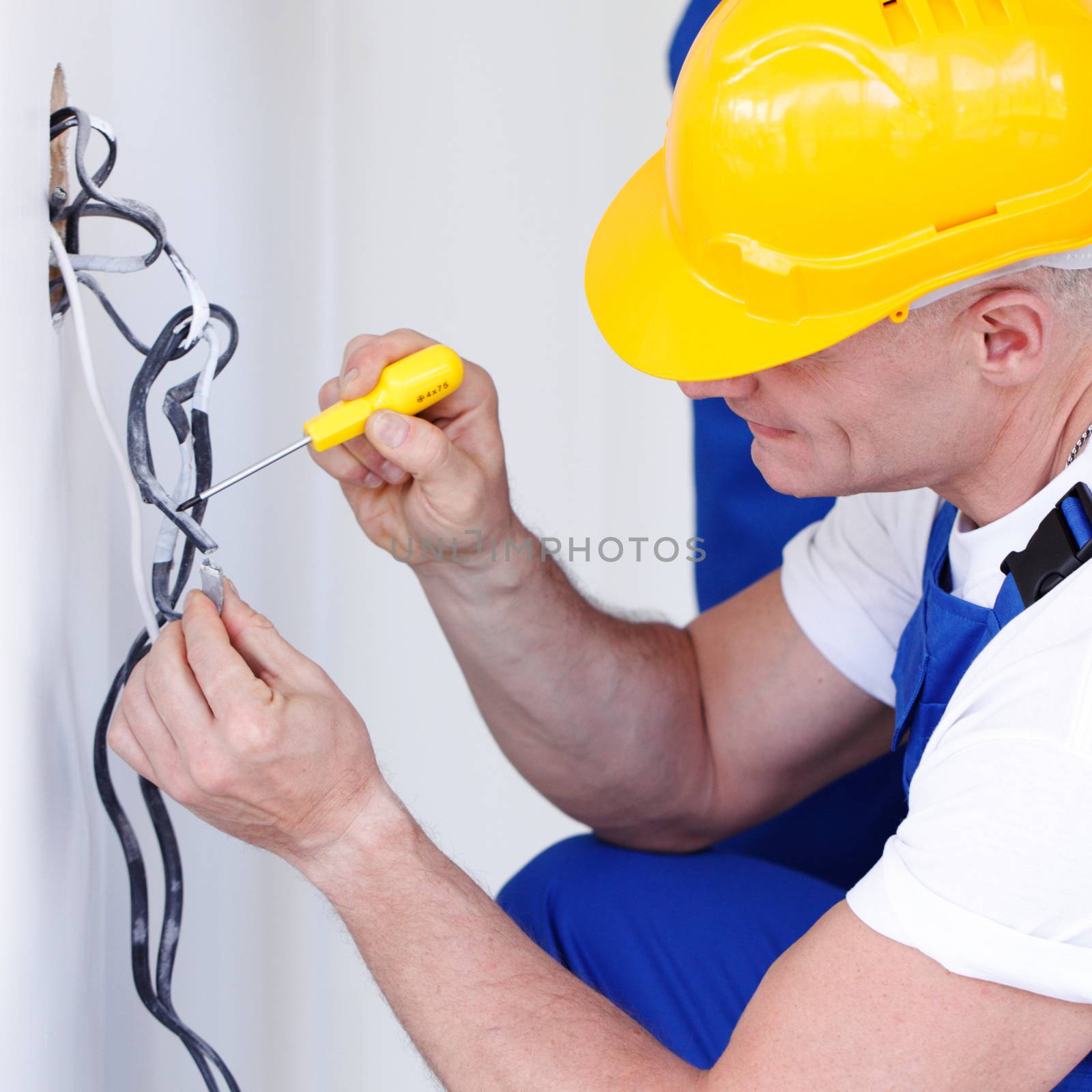 Electrician stripping electrical wires for wall socket