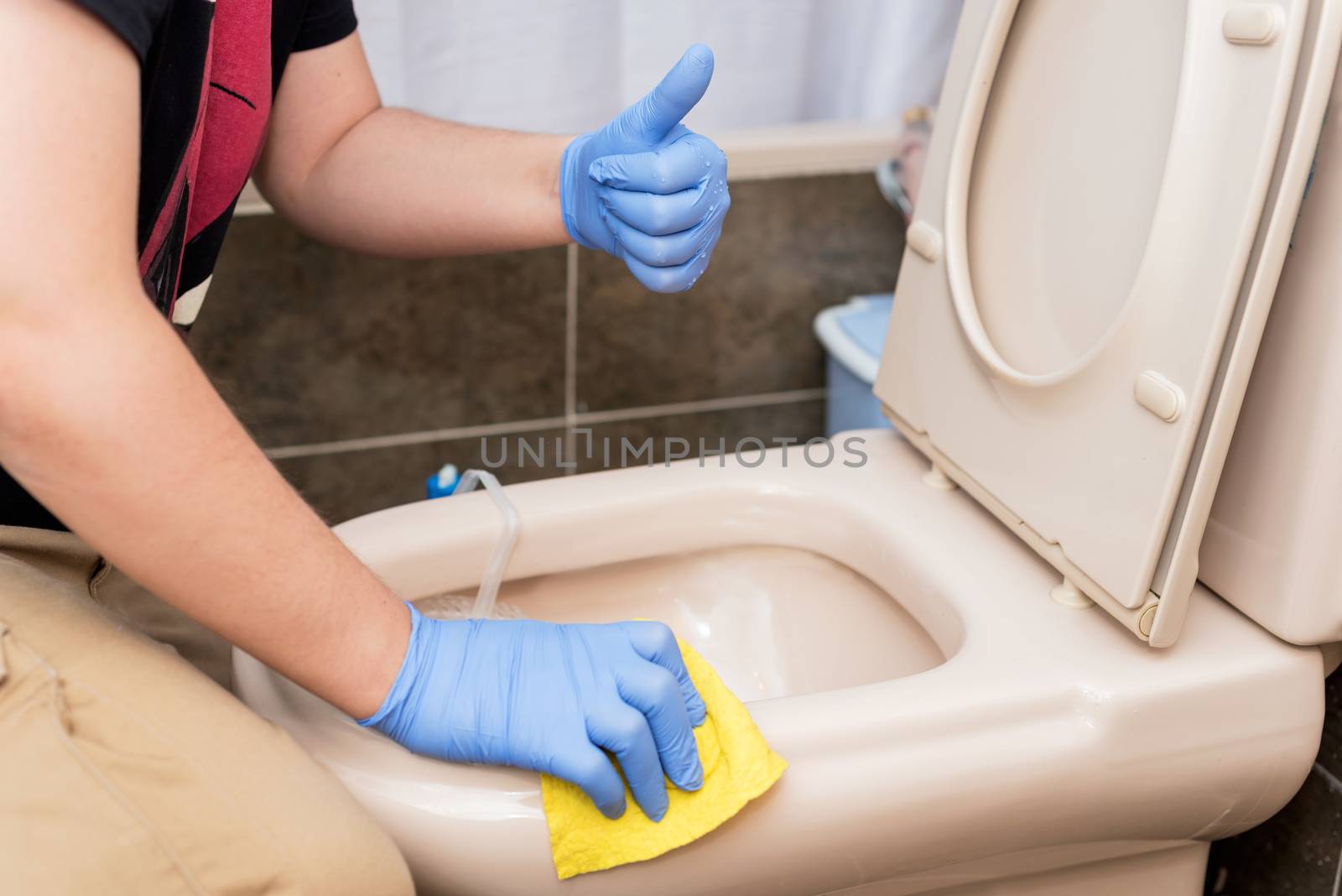 Man cleaning toilet bowl. Positive emotion showing thumbs up.