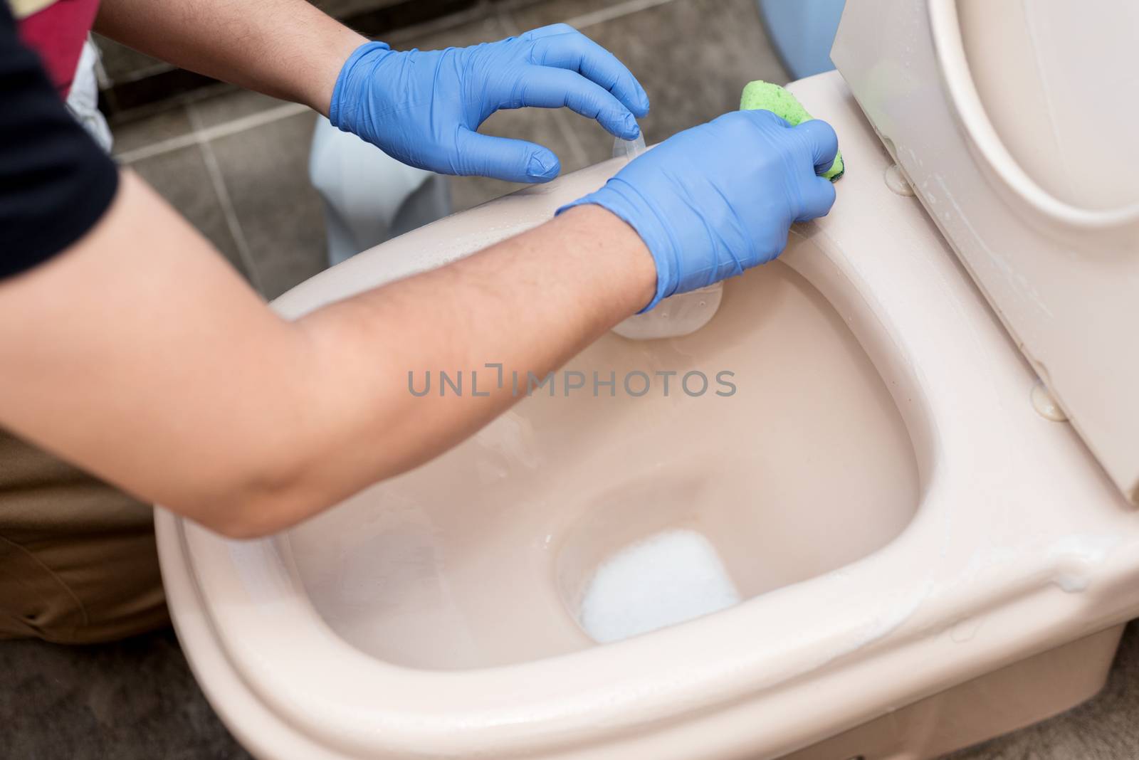 Man cleaning toilet bowl by HERRAEZ