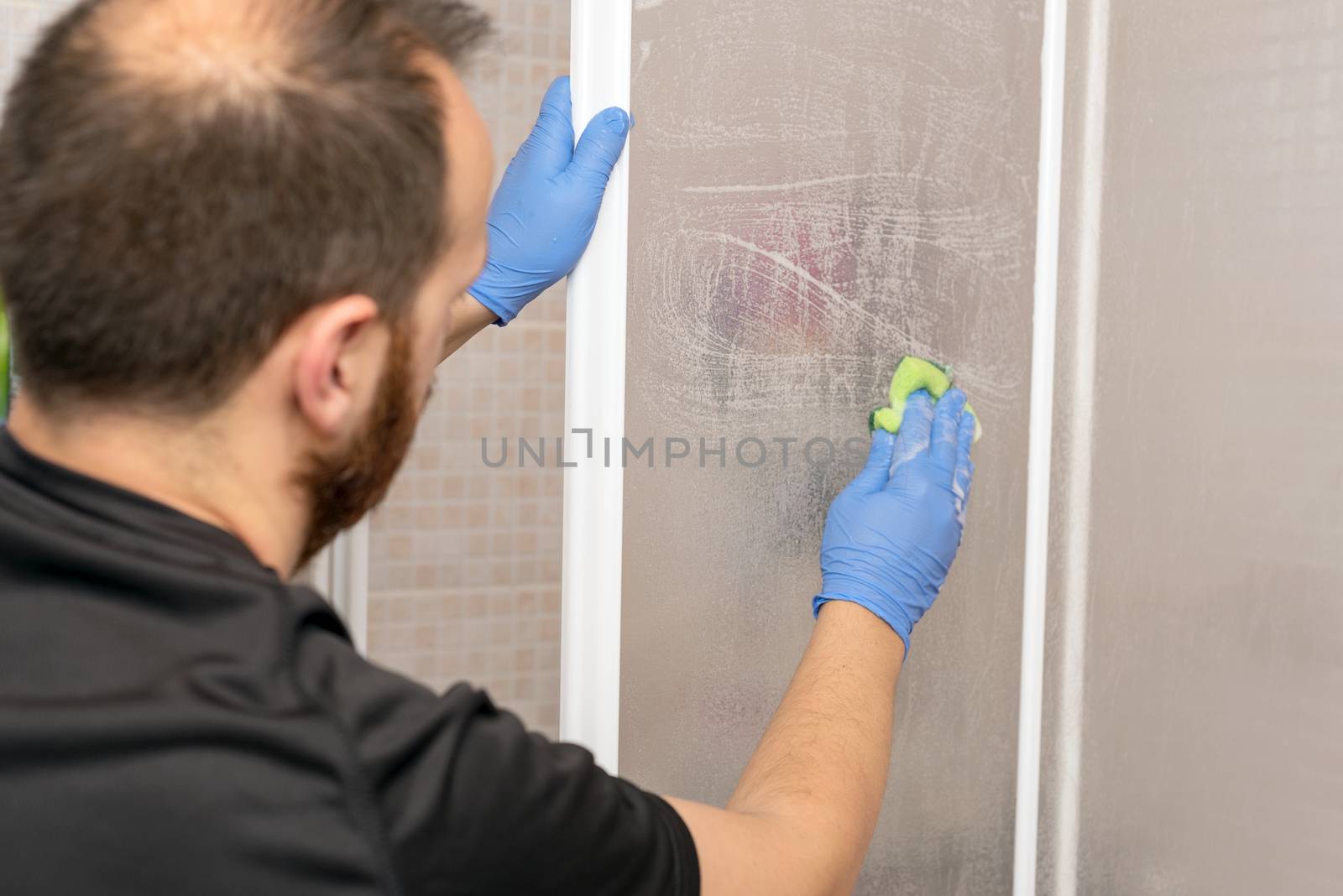 Man cleaning shower cabin. by HERRAEZ