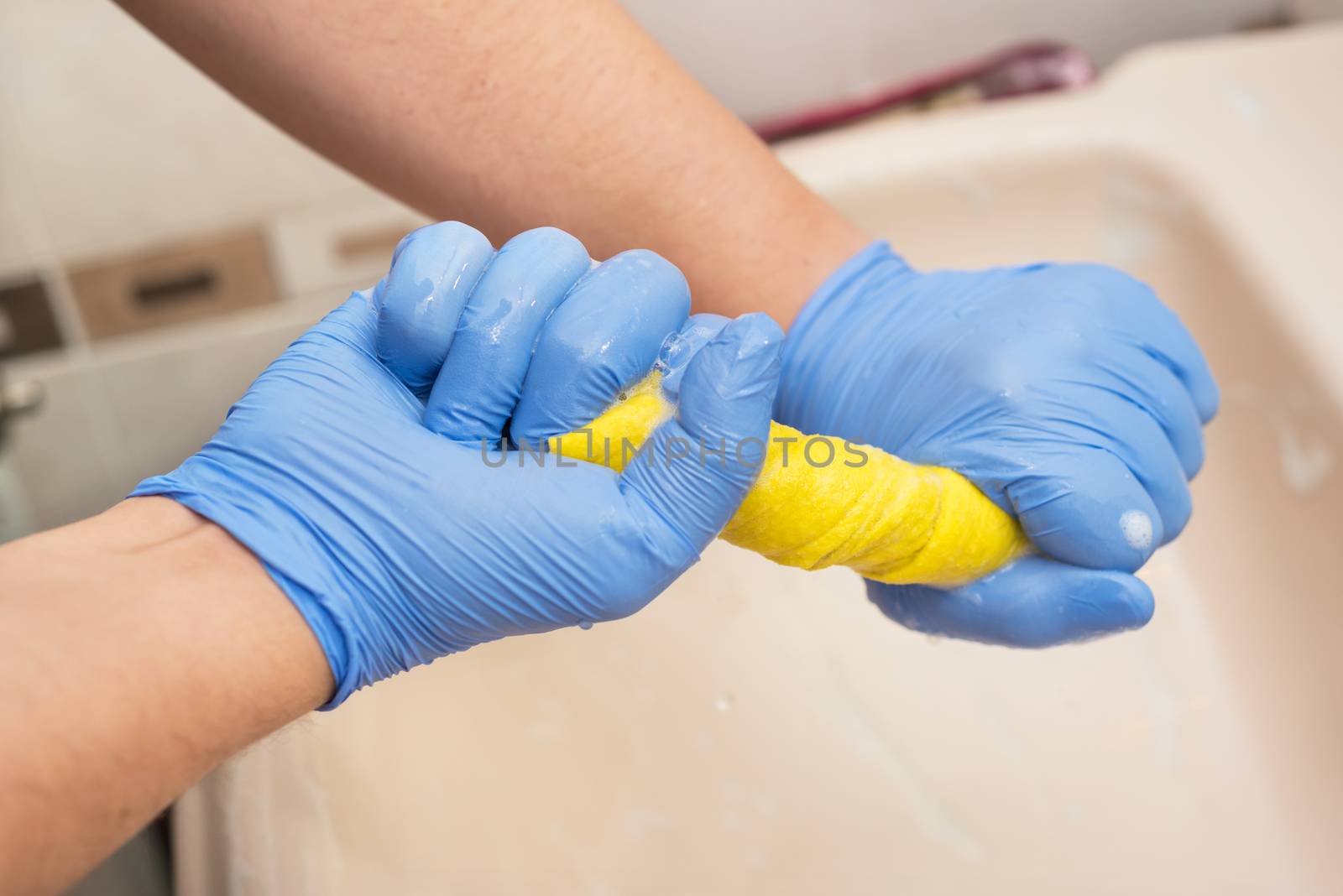 Man cleaning bathroom, draining a sponge cloth by HERRAEZ