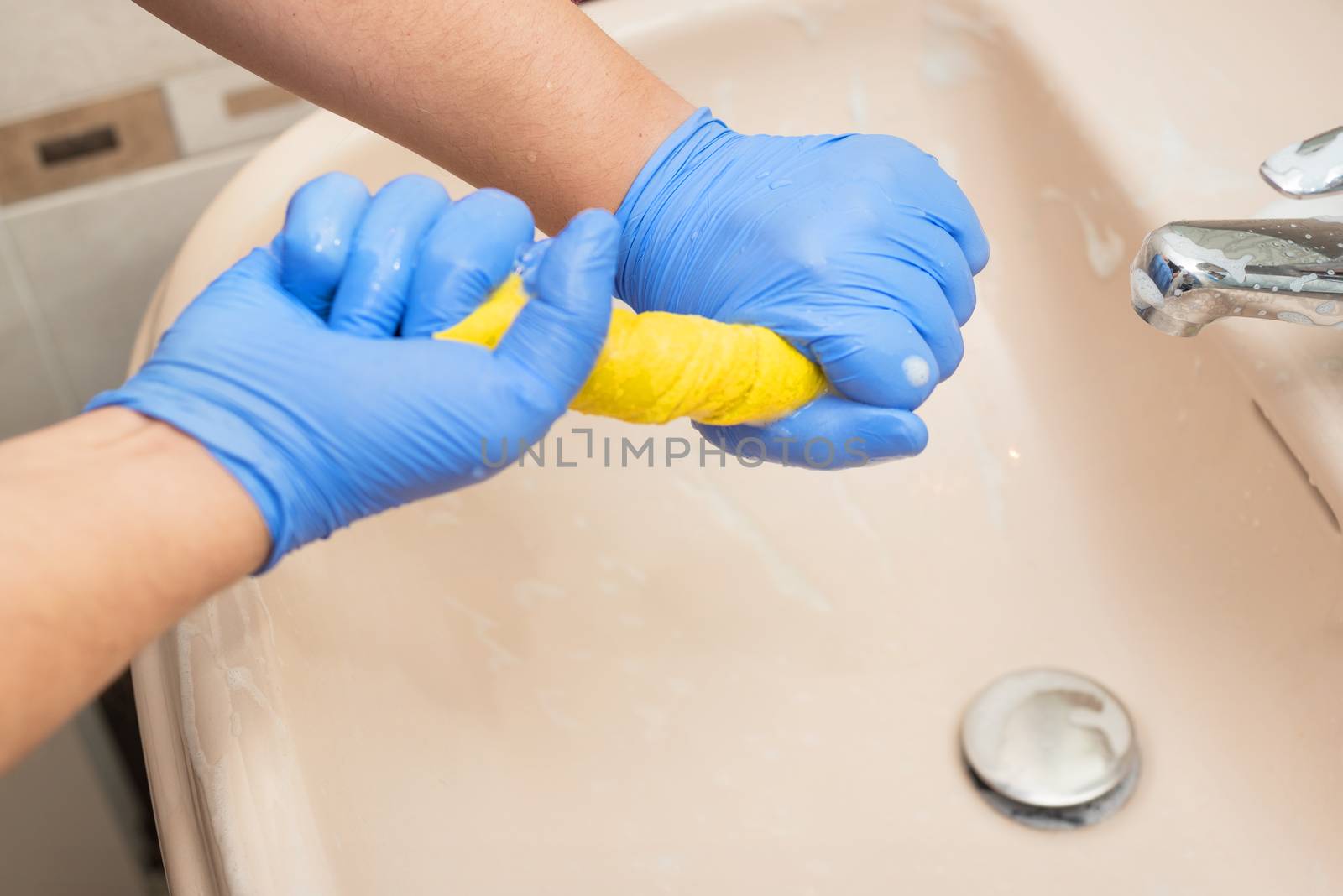 Man cleaning bathroom, draining a sponge cloth by HERRAEZ