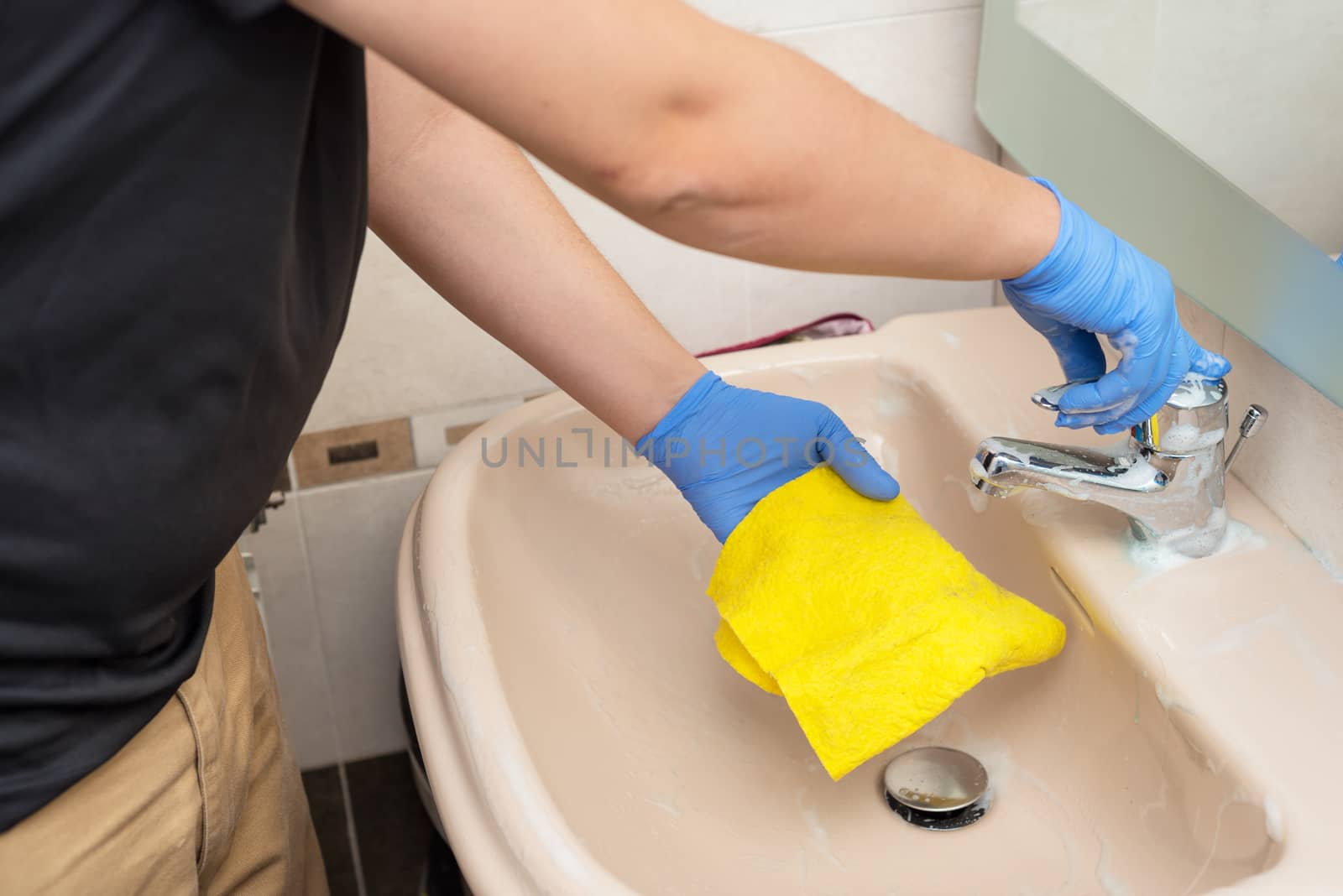 Man cleaning the bathroom sink by HERRAEZ