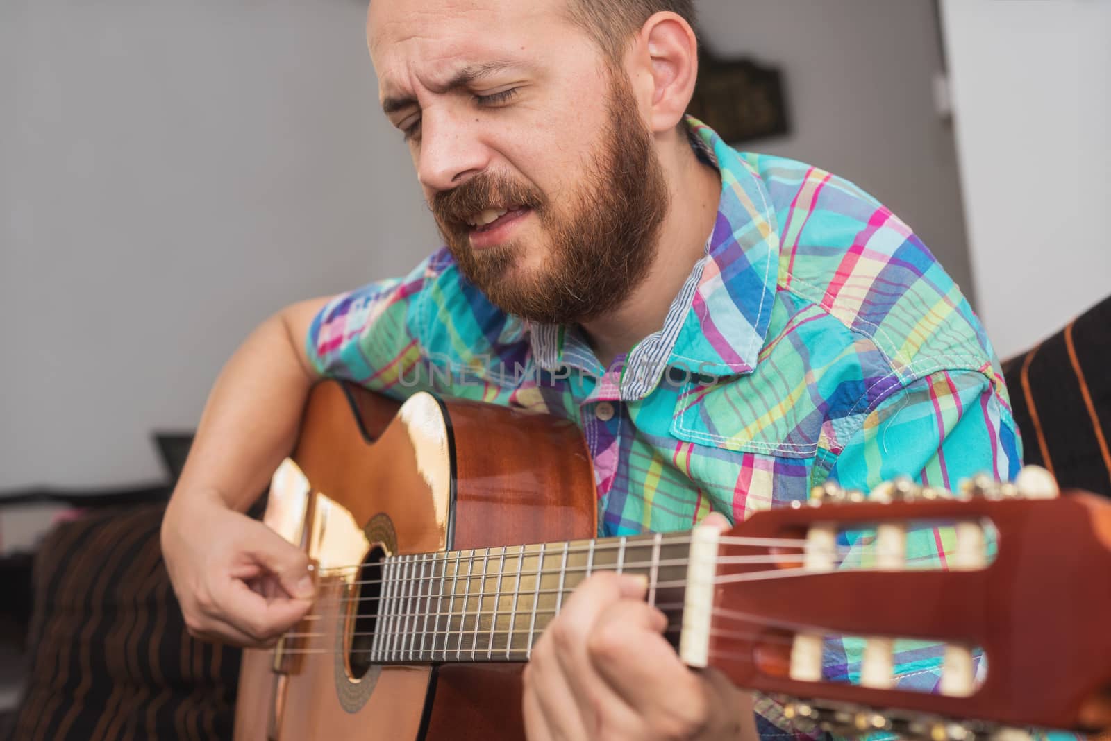 Young man musician playing acoustic guitar by HERRAEZ