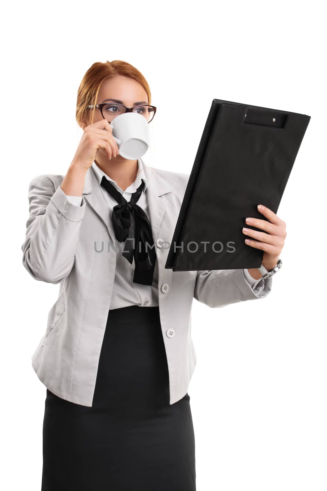 A portrait of a businesswoman drinking from a cup and looking at a clipboard, isolated on white background.