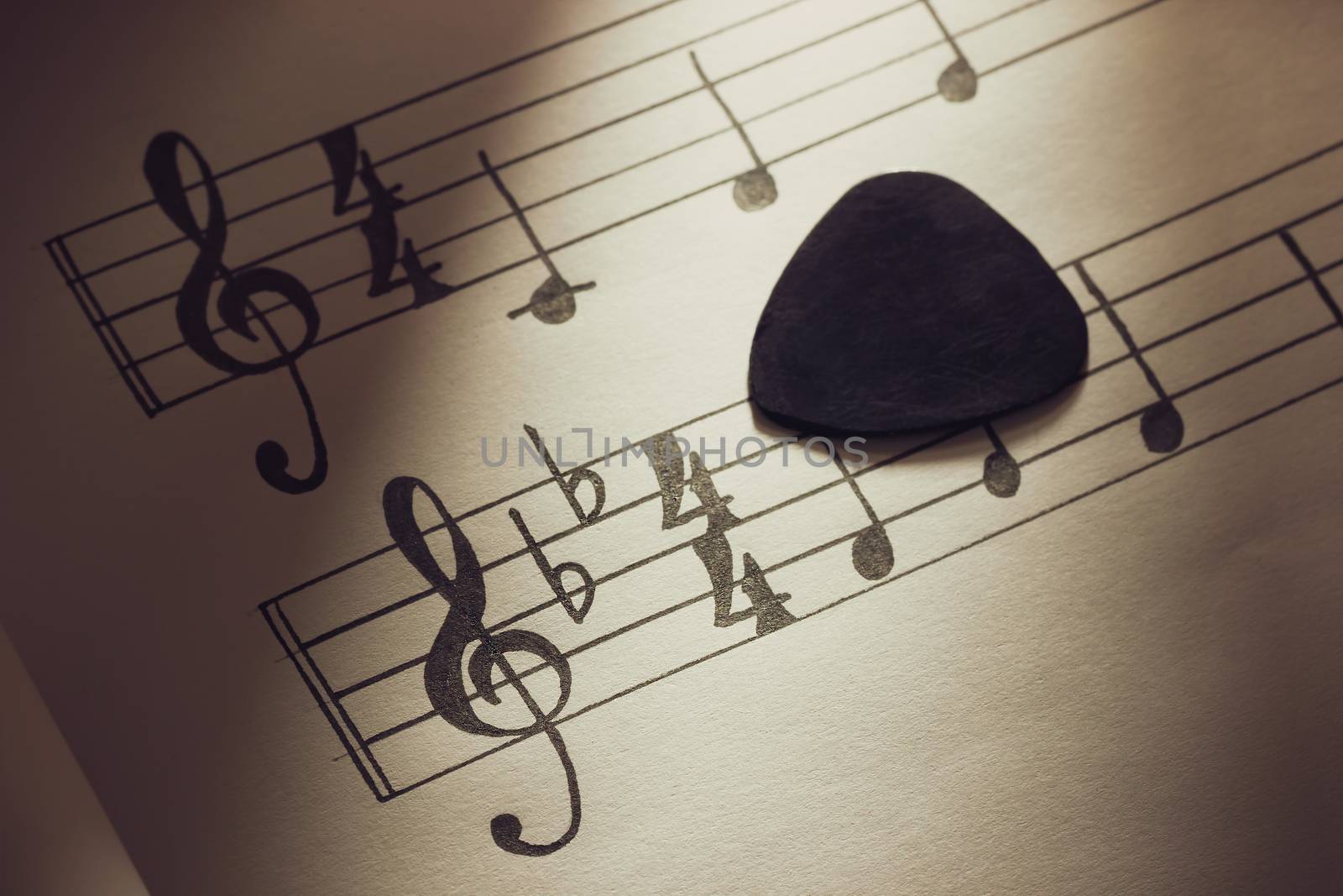 Music notes and black guitar pick  in morning light. Closeup and copy space for text. Concept of Music lovers.