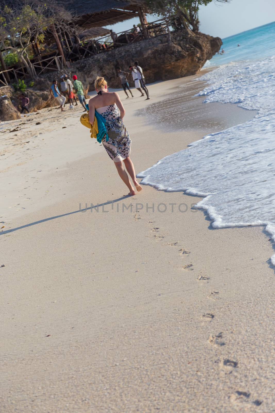Woman running on the beach in sunset. by kasto