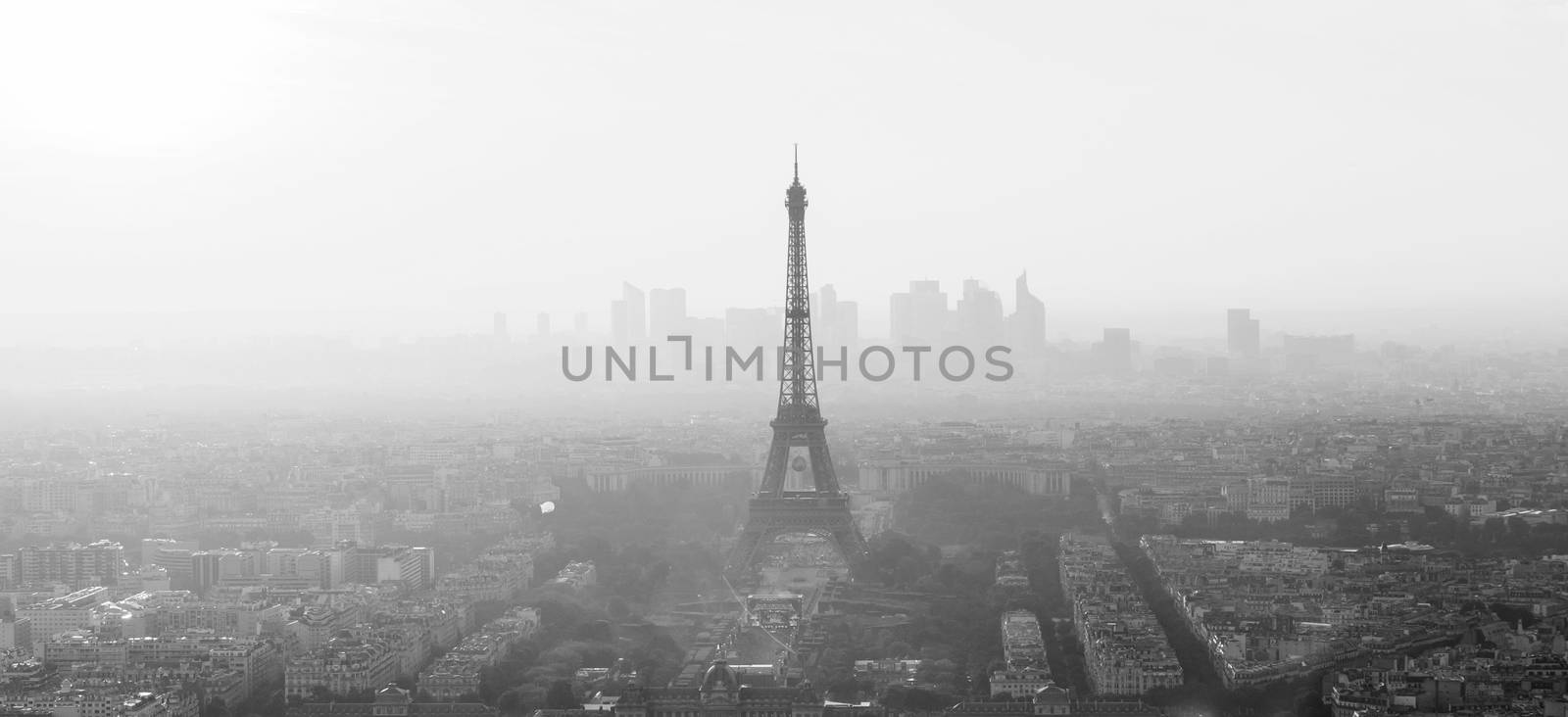 Aerial view of Paris with Eiffel tower and major business district of La Defence in background at sunset. Black and white image.