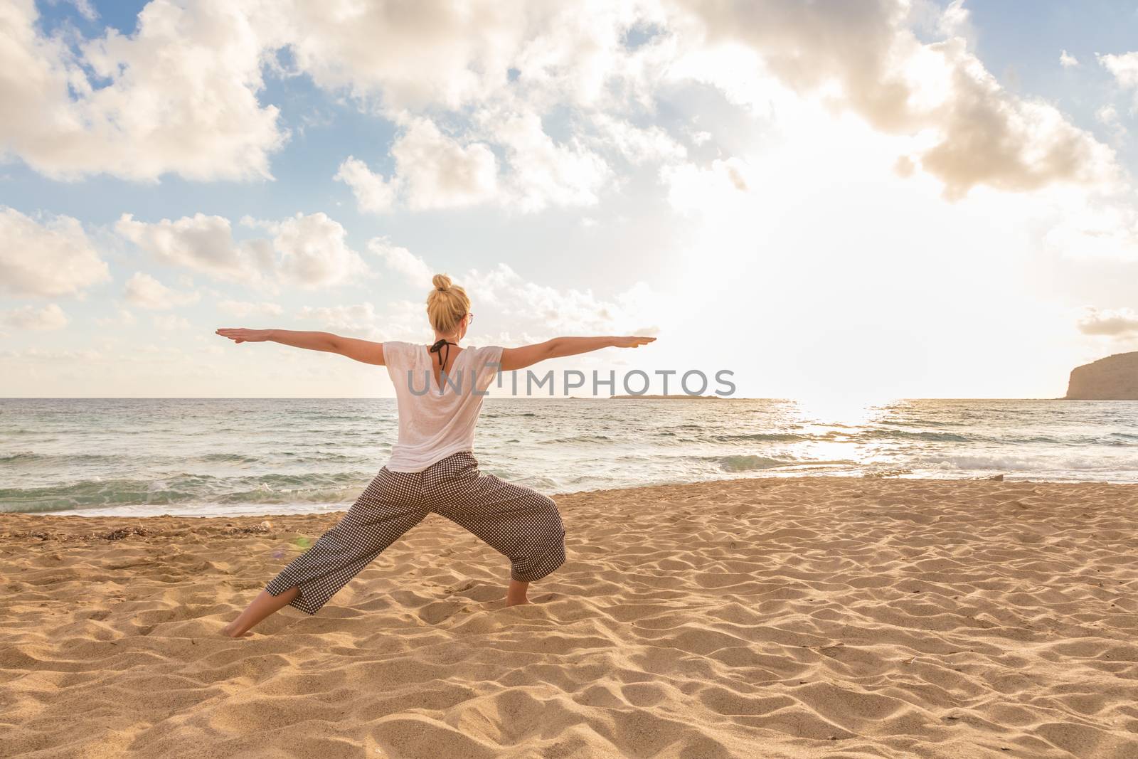 Woman practicing yoga on sea beach at sunset. by kasto