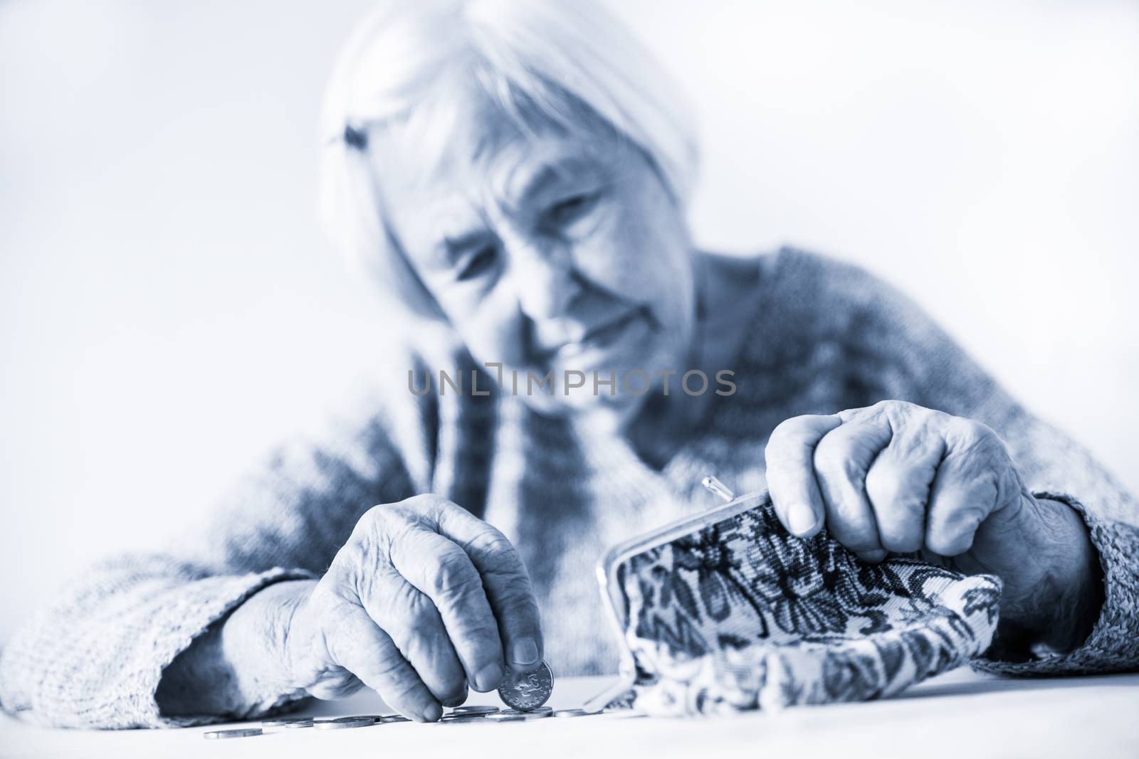 Concerned elderly 96 years old woman sitting at table at home and counting remaining coins from pension in her wallet after paying bills. Unsustainability of social transfers and pension system.