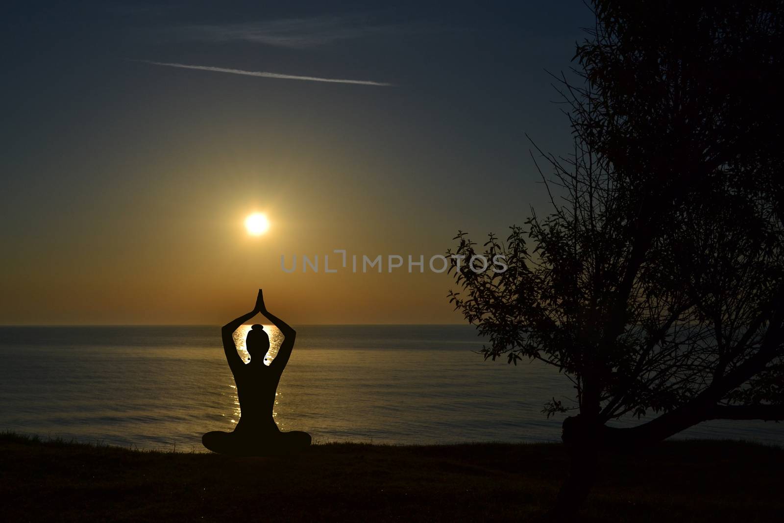 Silhouette of young woman practicing yoga on the beach at sunris by hibrida13