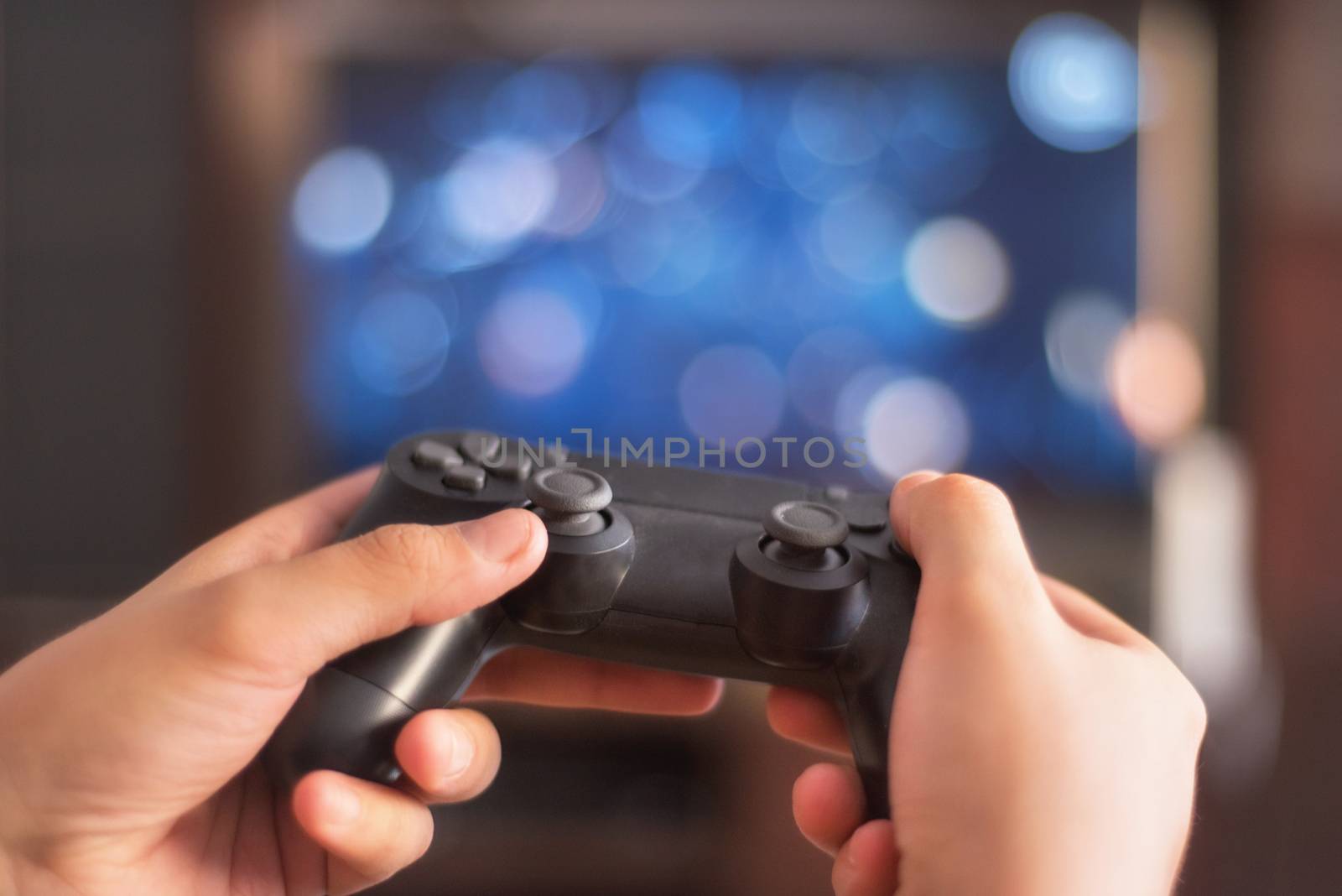 Man hold game pad in front of tv screen by HERRAEZ