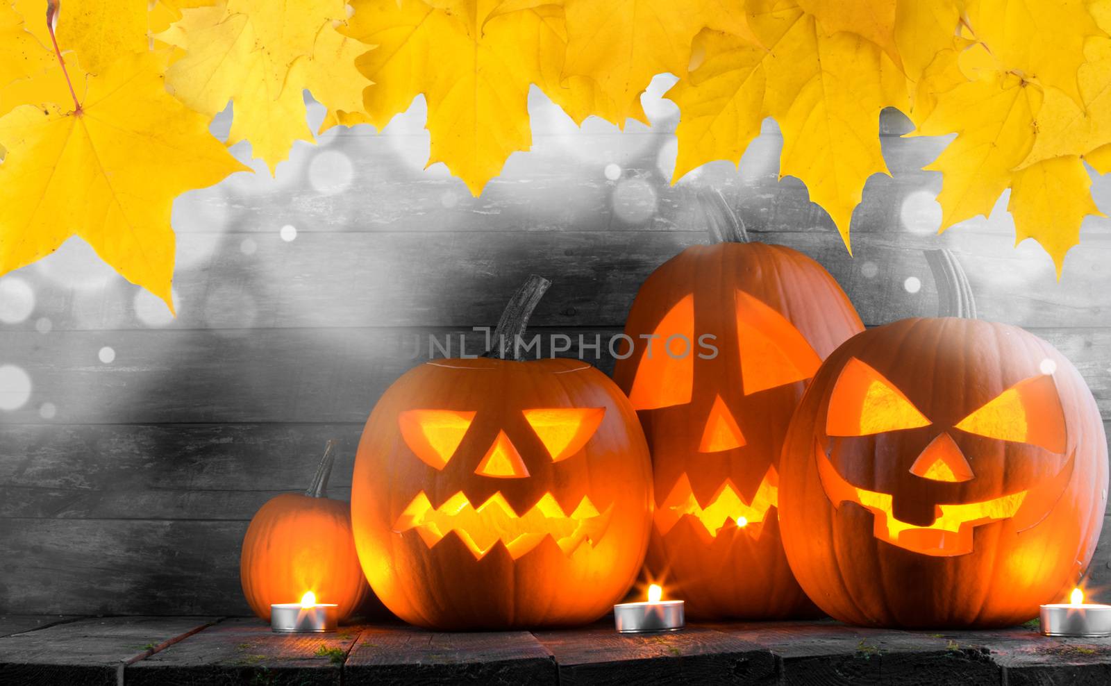 Group of Halloween pumpkin head jack o lantern and candles on dark wooden background , bokeh lights and autumn yellow maple leaves frame