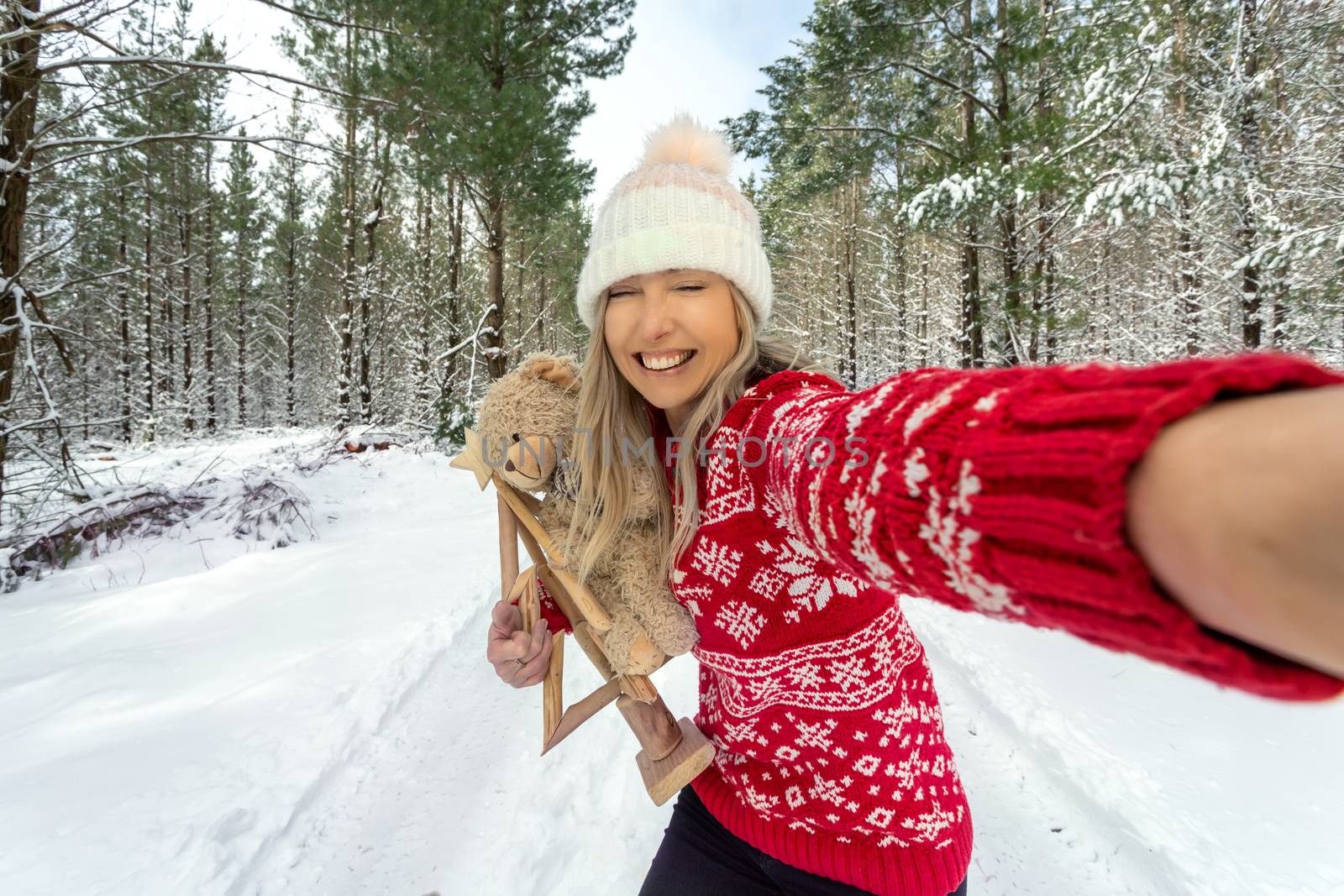 Cheerful girl takes a selfie among the tall snow covered pines Christmas