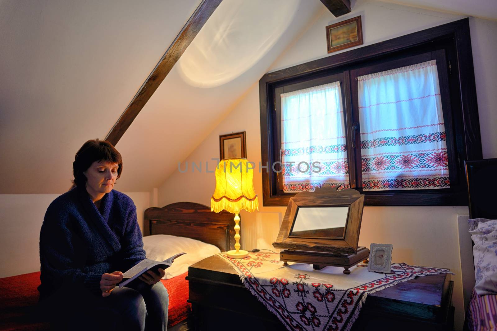 Female reading book on bed in traditional house