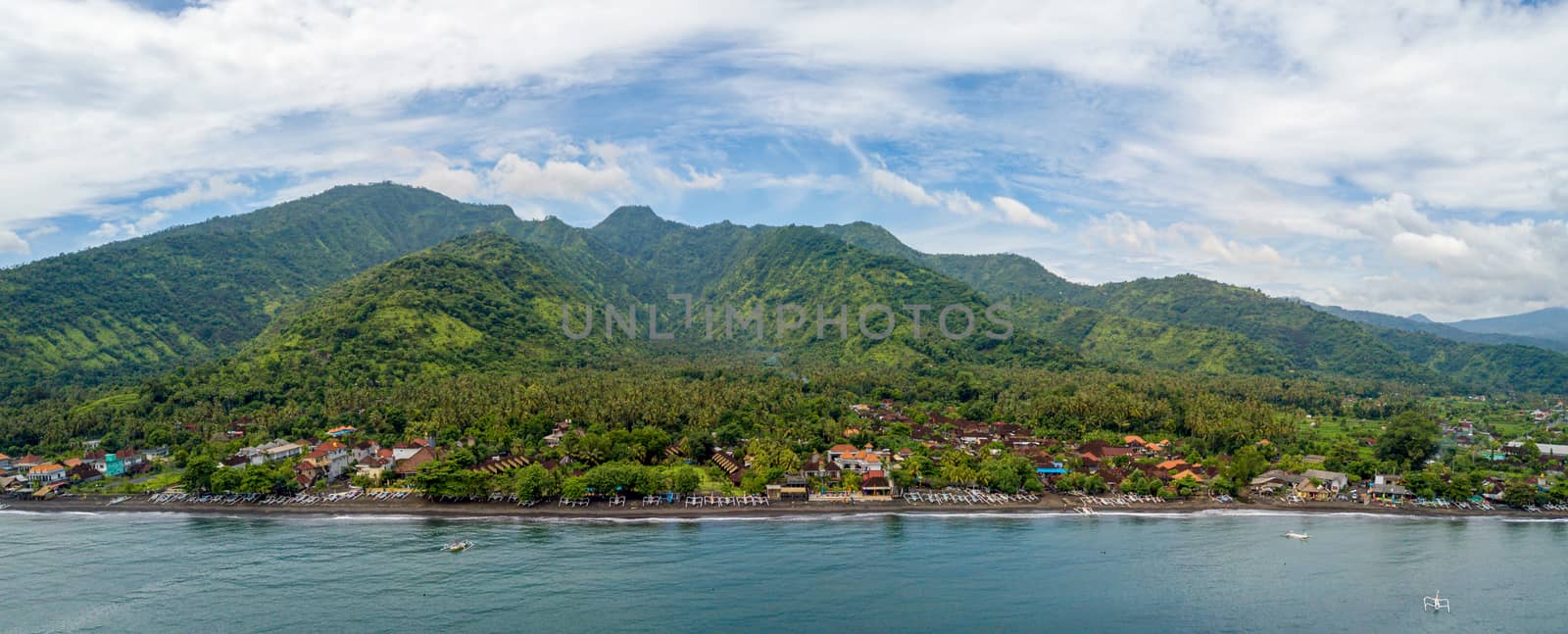 Panoramic aerial view of Amed beach in Bali, Indonesia. Traditional fishing boats called jukung on the black sand beach.
