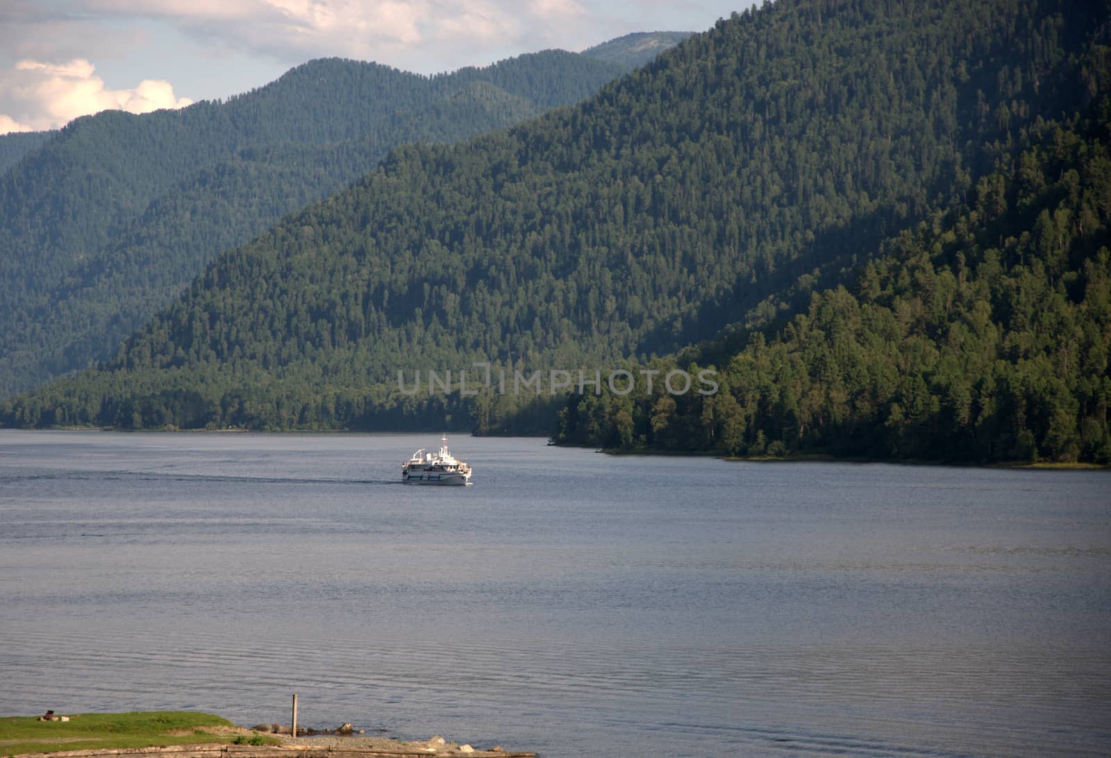 Passenger ship sailing on the lake surrounded by high mountains overgrown with coniferous forest. Teletskoye Lake, Altai, Siberia, Russia.