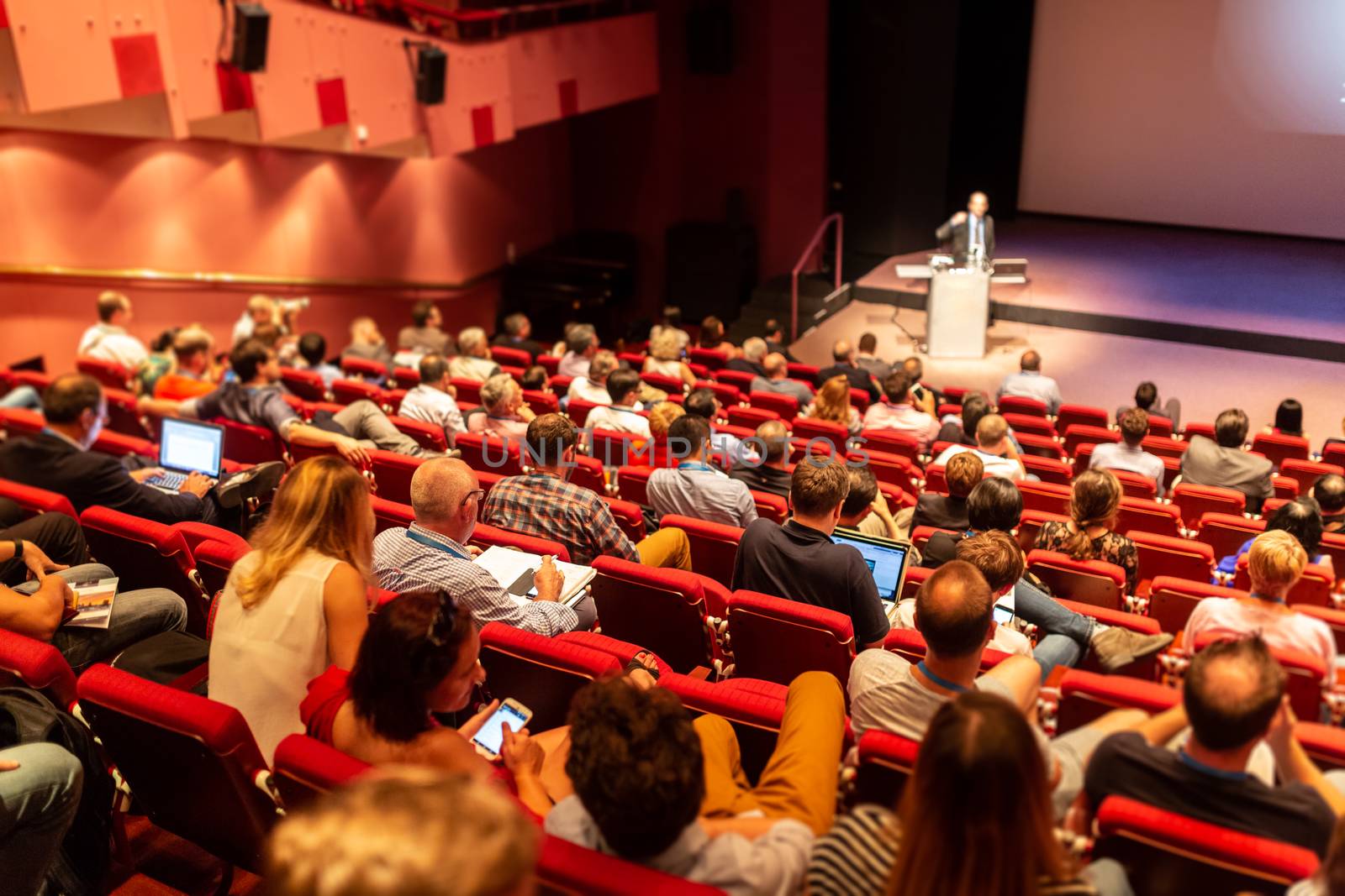 Speaker giving a talk in conference hall at business event. Audience at the conference hall. Business and Entrepreneurship concept. Focus on unrecognizable people in audience.