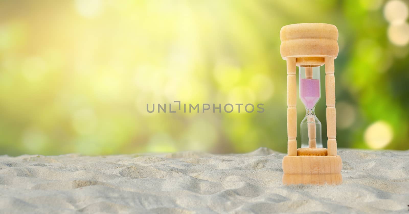 Hourglass set on a white sand background, natural green background, time concept by sarayut_thaneerat