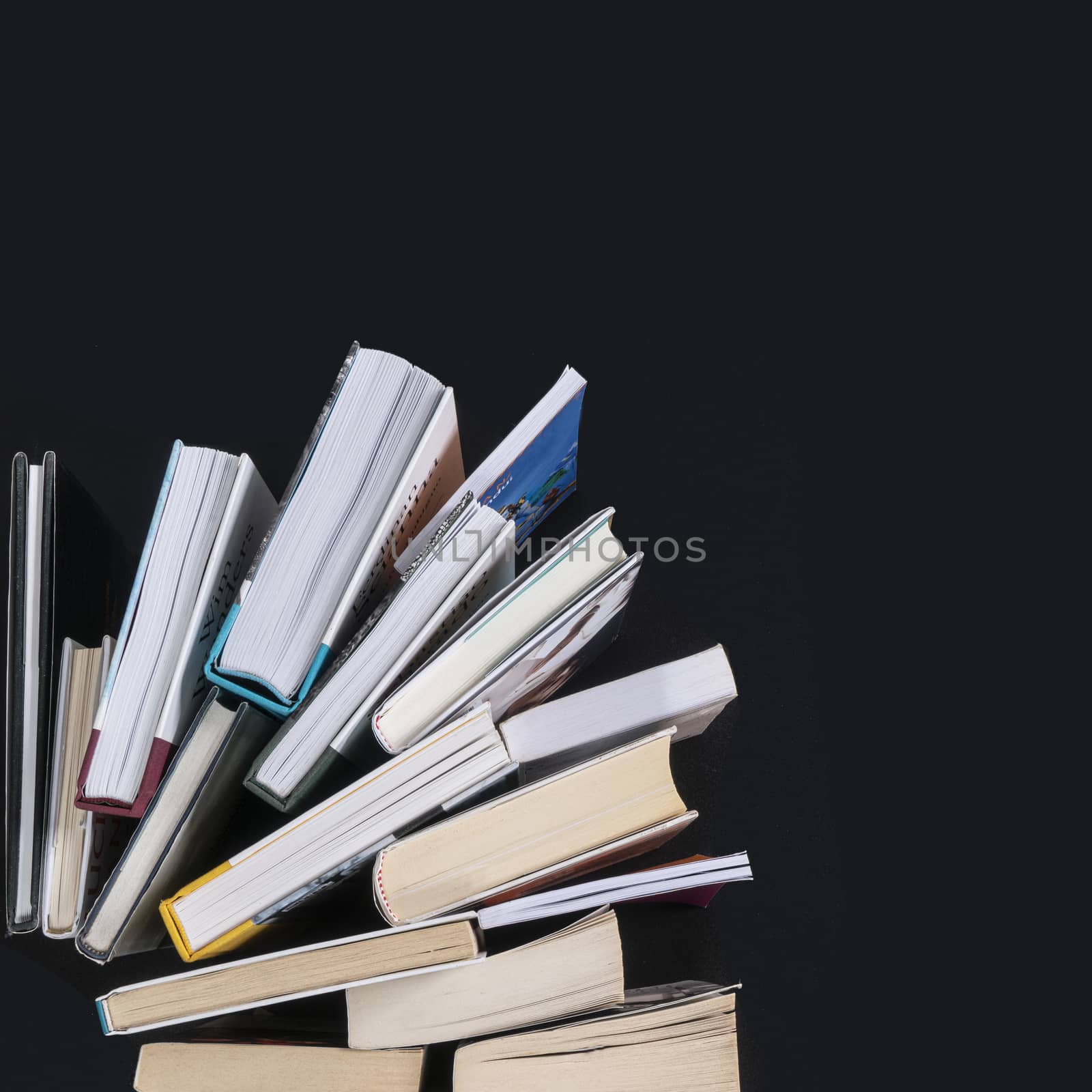 a series of books arranged like a fan on a black surface seen from above