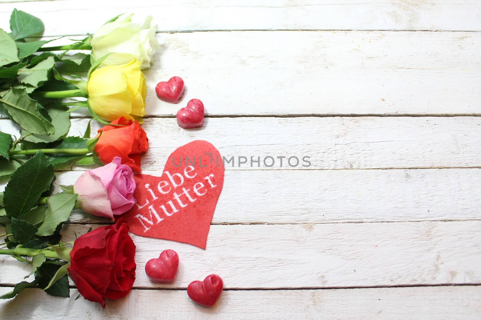 The picture shows a beautiful decoration with roses and a heart with the german text dear mother.
