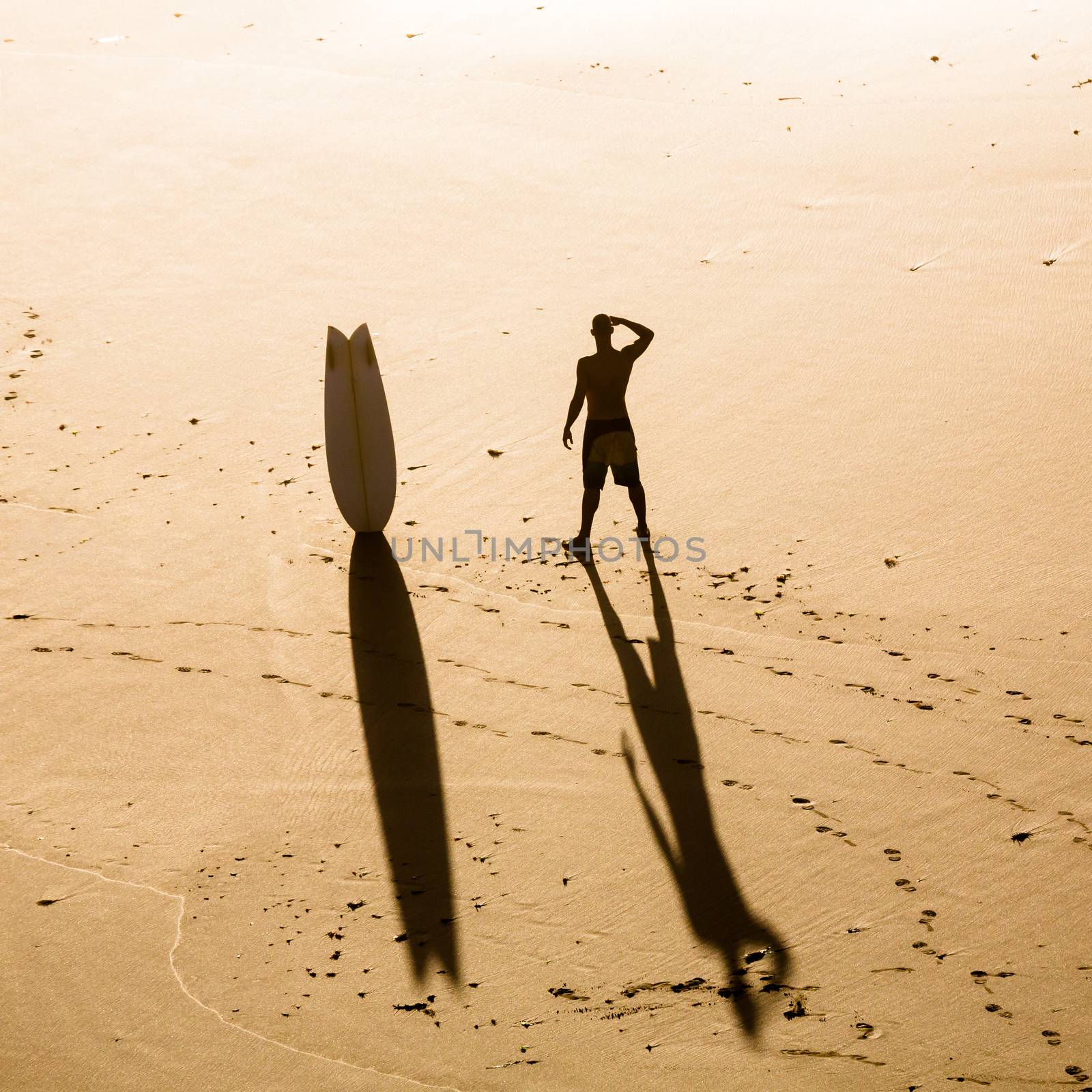 Top view of a surfer on the beach checking the waves