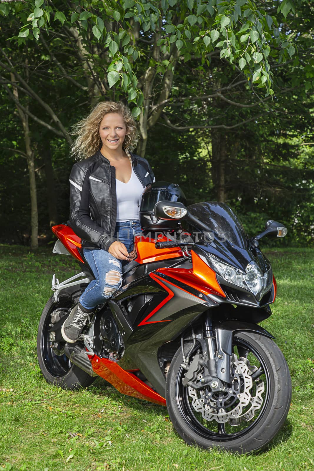 Twenty something woman, with happy expression, sitting on a sport motocycle