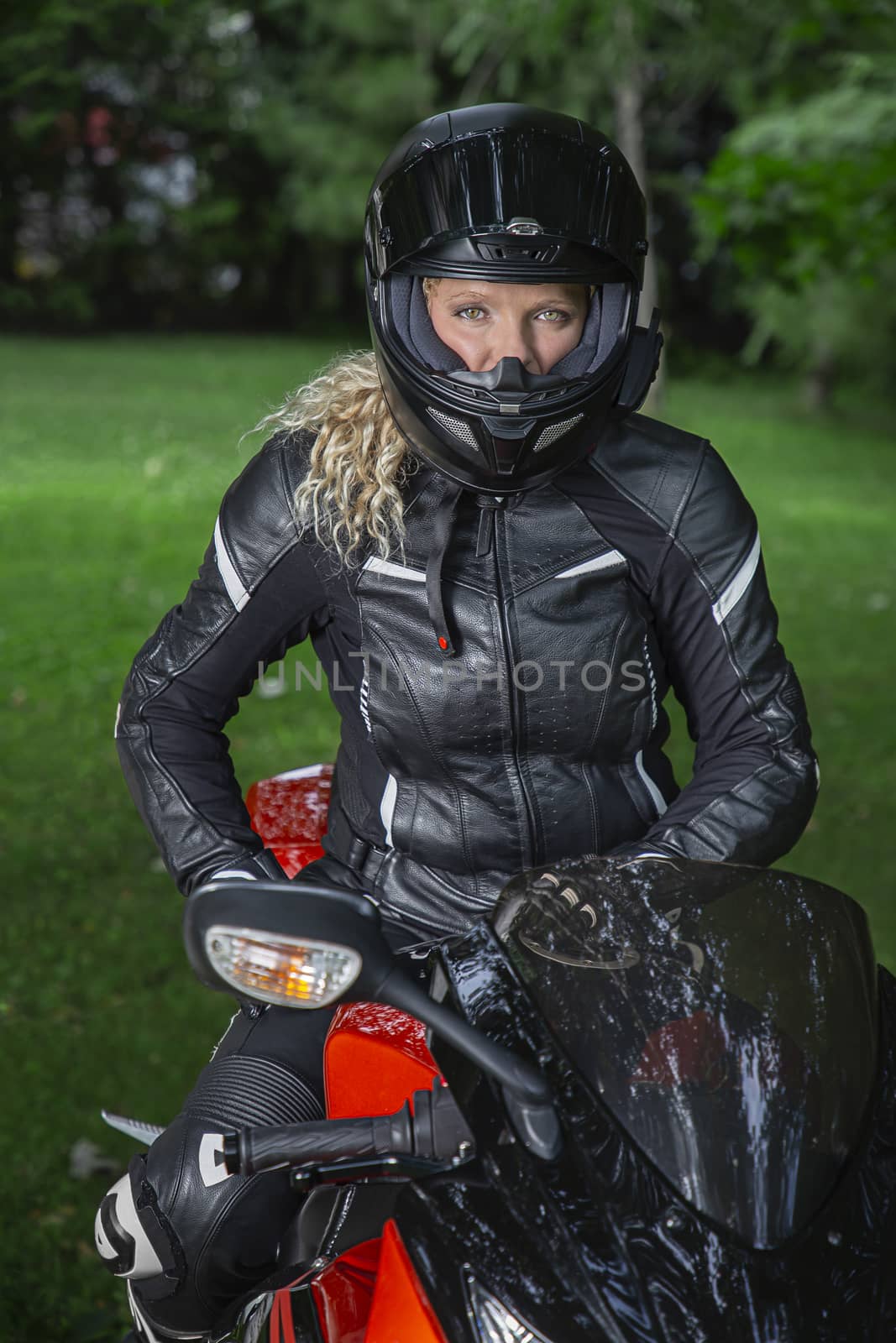 Twenty something woman, wearing full motocyclist outfit, sitting on a sport motocycle