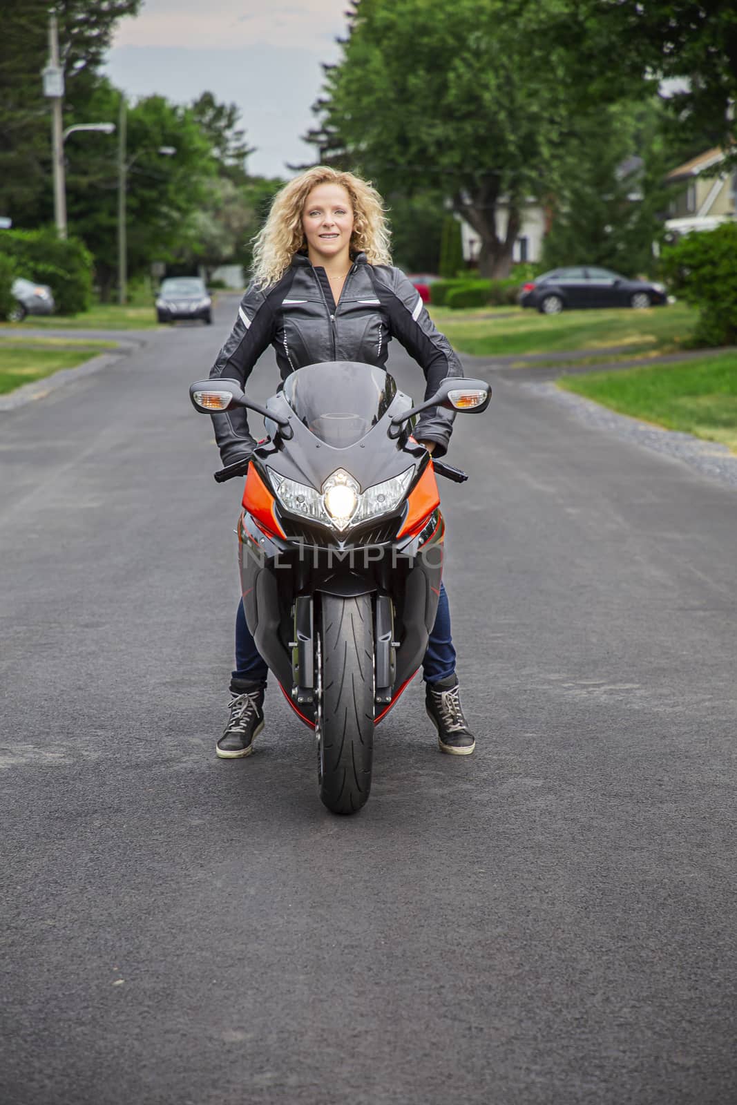 twenty something woman, sitting a on sport motocycle, in the middle of a rural street