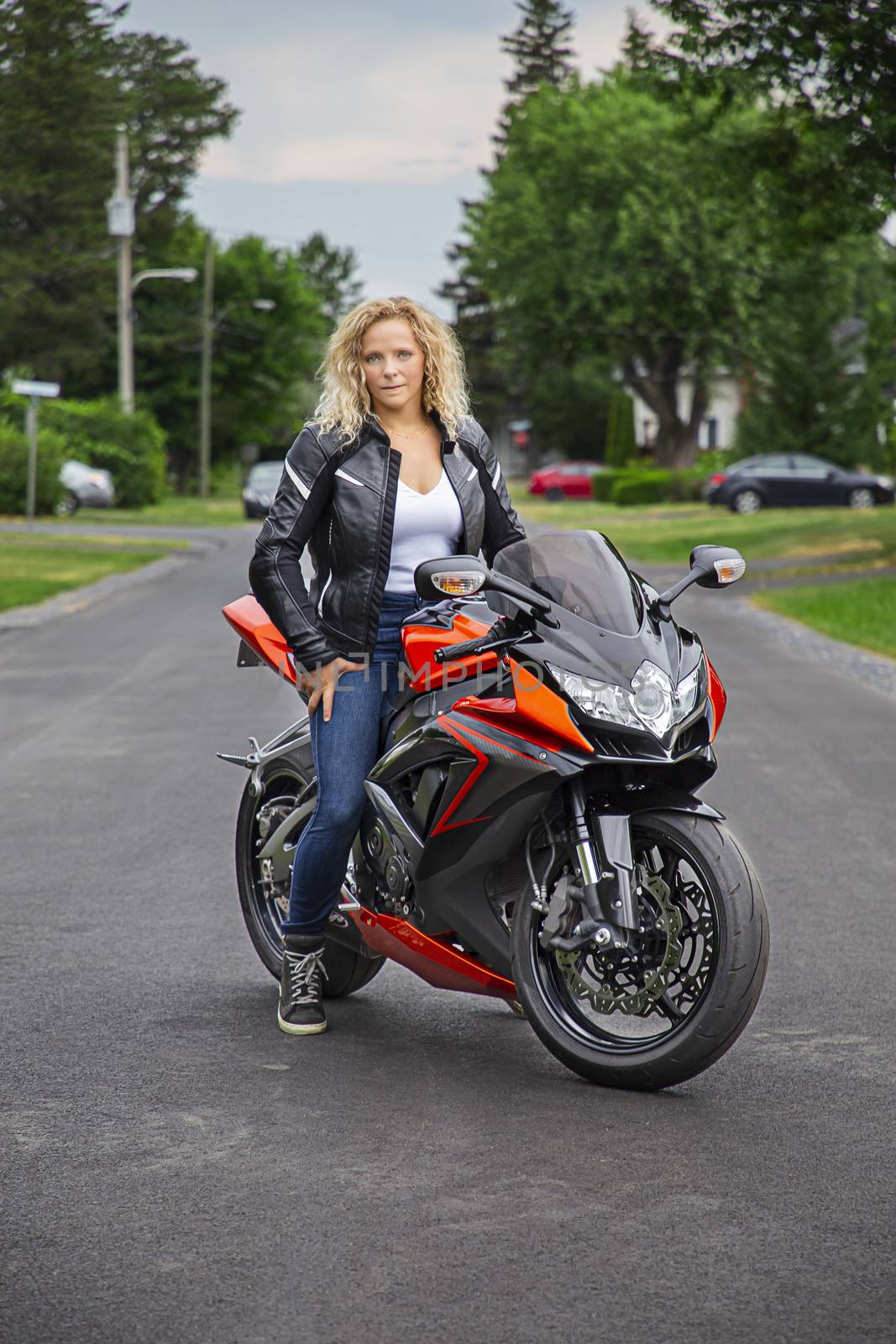 young woman, sitting on a sport motocycle, in a suburb street