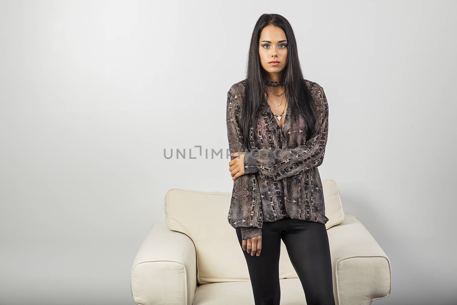 twenty something woman, wearing stylish clothes, standing in front of a white couch
