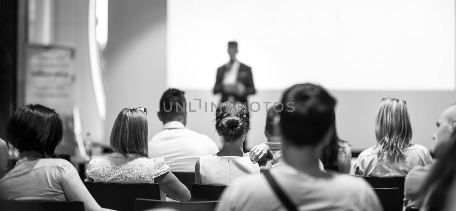 Speaker giving talk at business event. Audience at the conference hall. Business and Entrepreneurship concept. Focus on unrecognizable people in audience. Black and white photo.