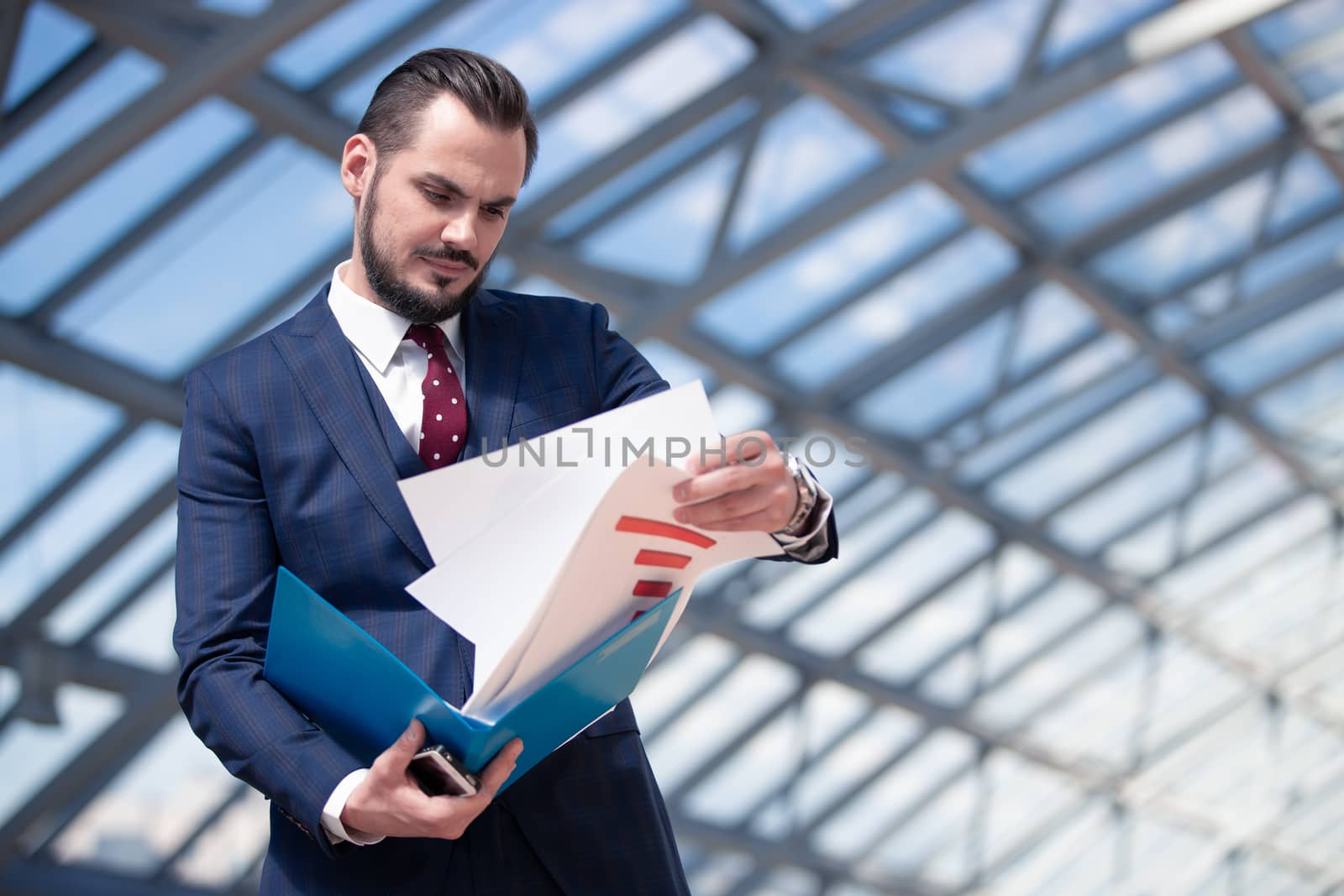 Busenessman reading a report or other document in modern builing with glass ceiling