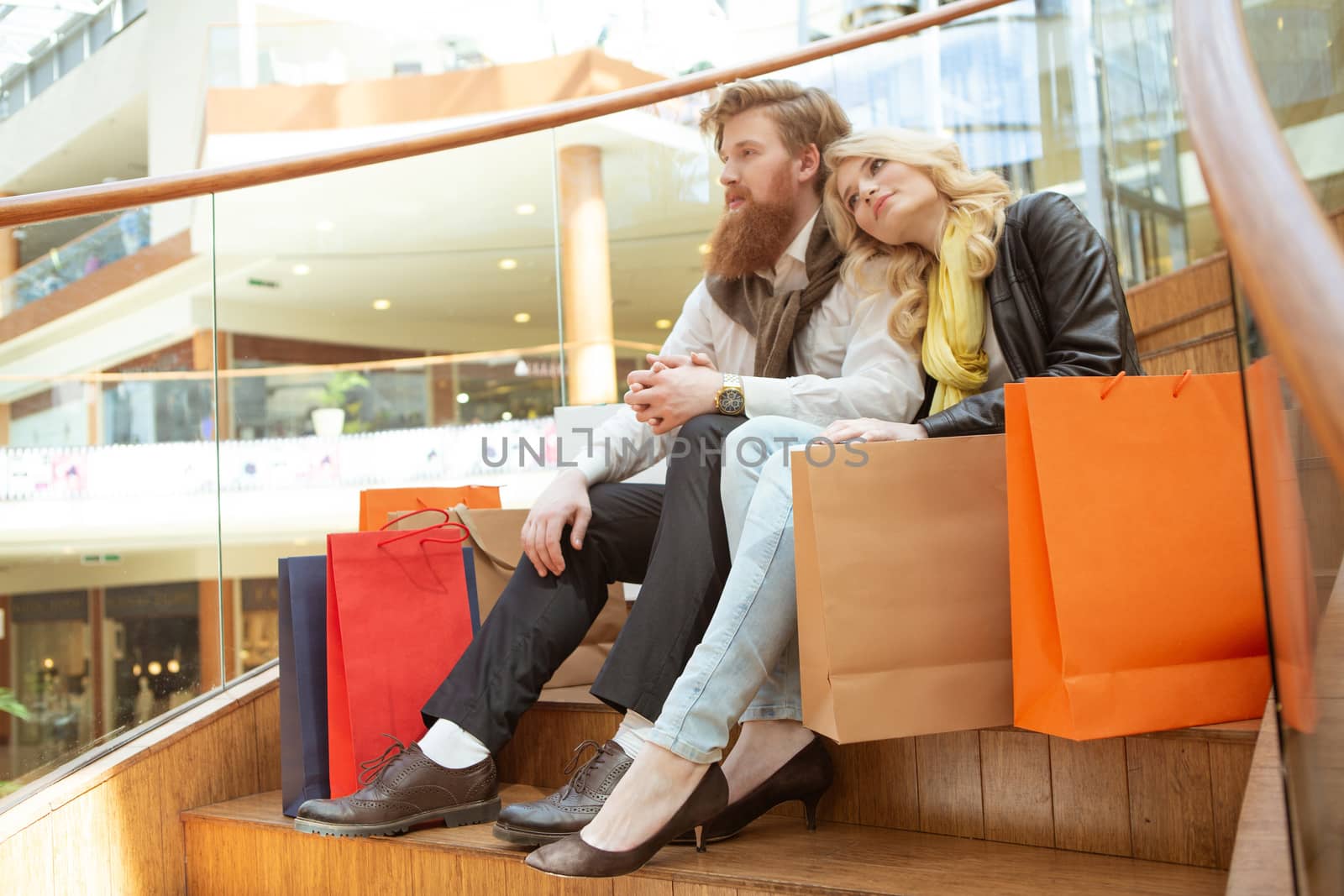 Happy beautiful young couple with shopping bags in mall