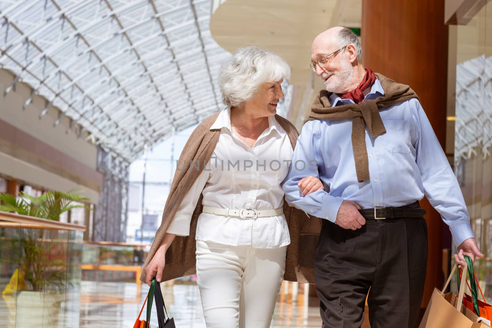 Adult senior couple with purchases in bags at shopping mall