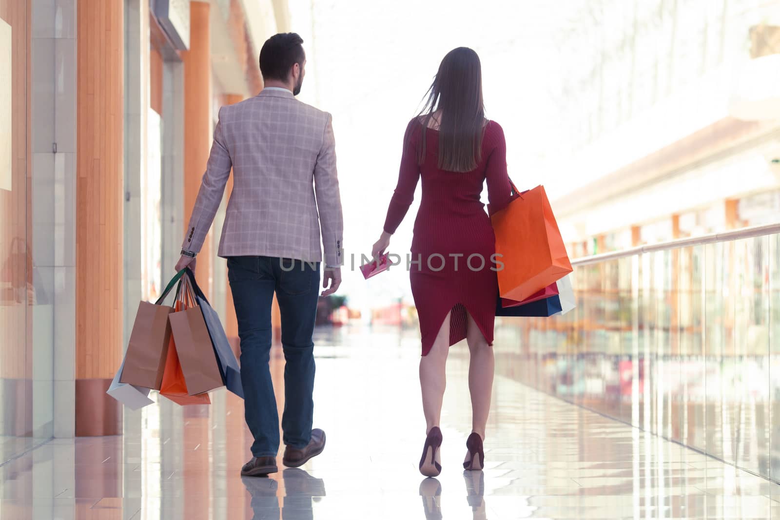 Happy beautiful young couple walking in mall holding shopping bags