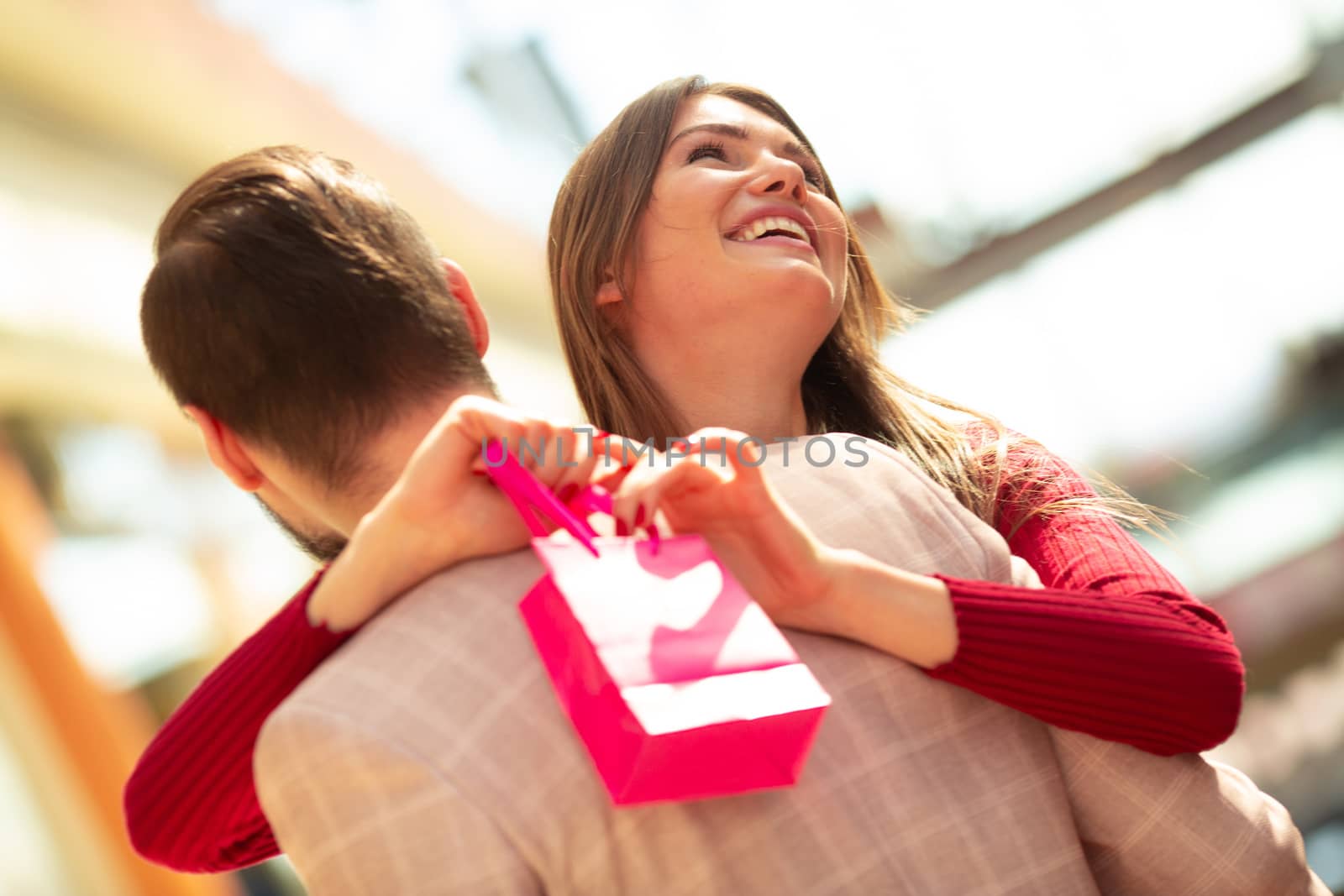 Smiling couple embracing at shopping mall holding paper bags