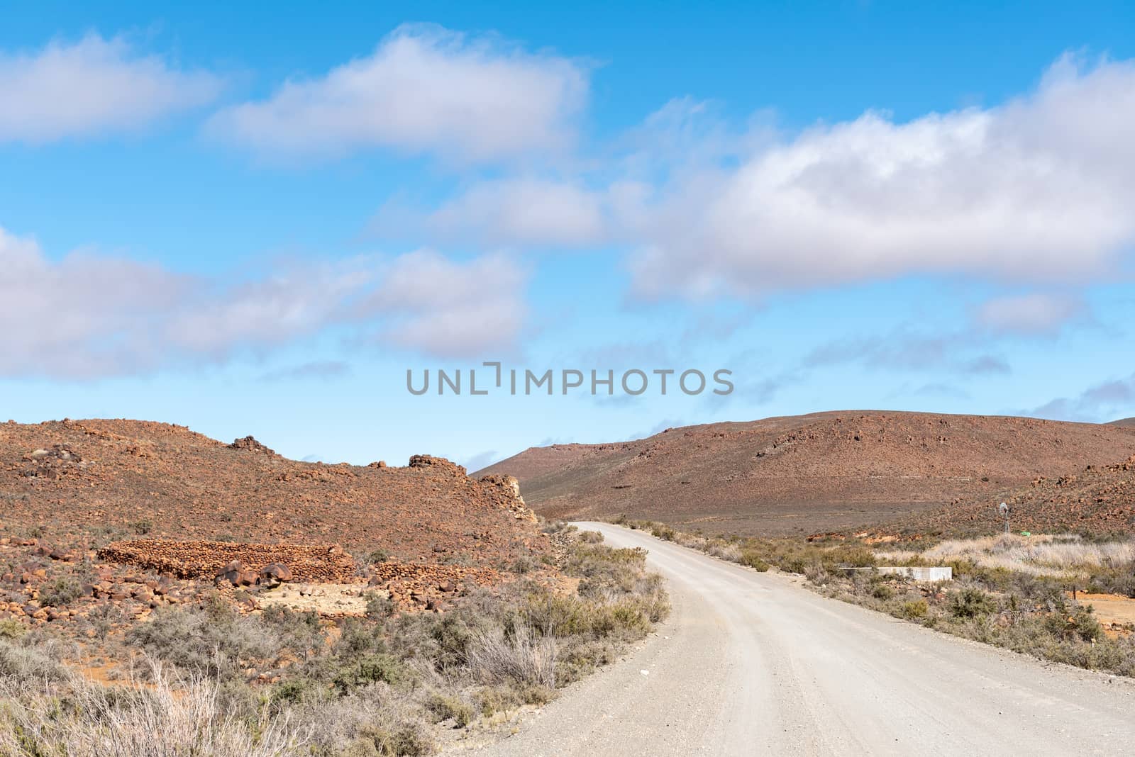 A farm landscape on road R356 between Fraserburg and Sutherland in the Northern Cape. Old stone livestock enclosures, a dam and a windmill are visible