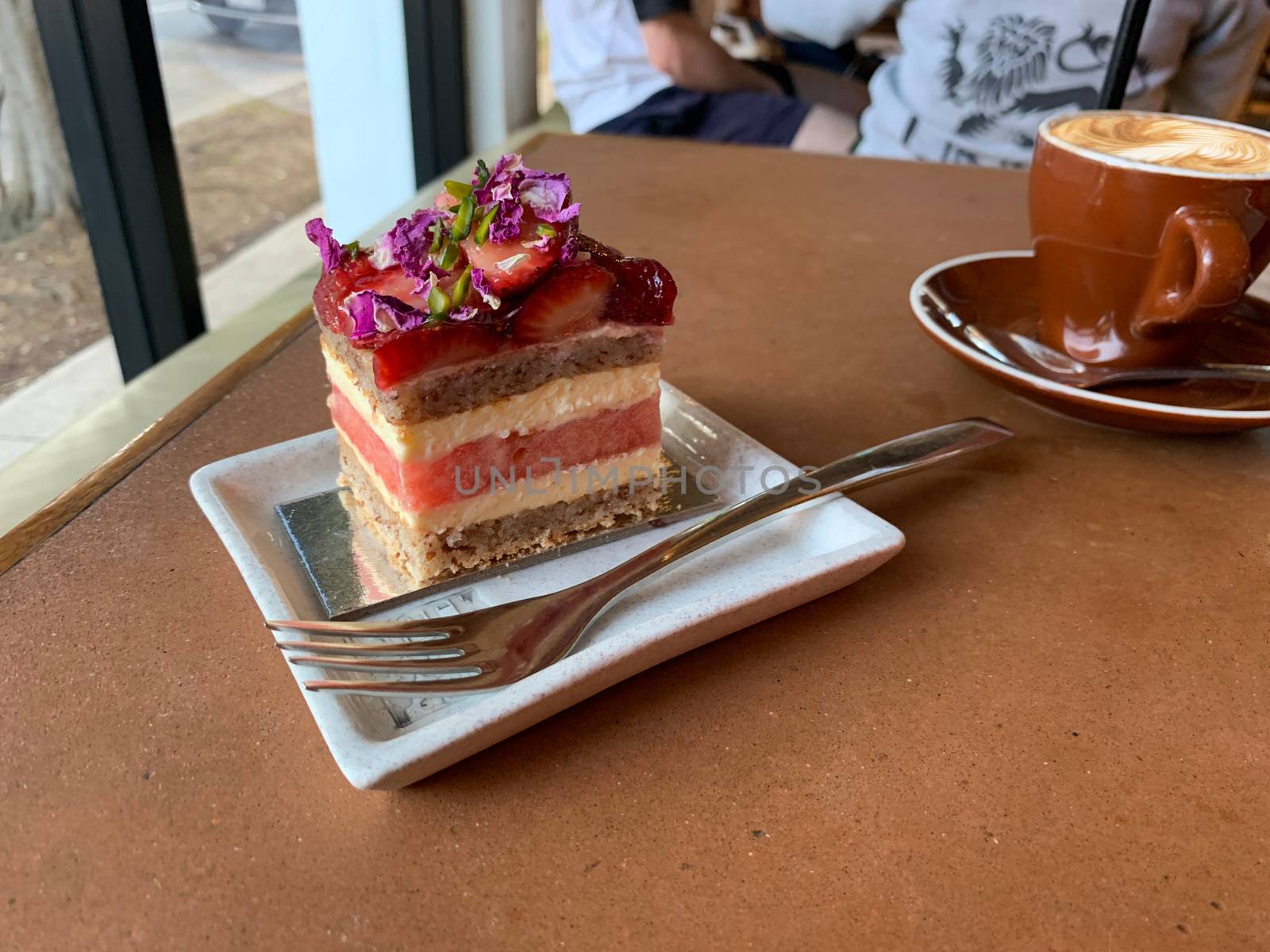 Straberry and watermelon layer cake with a cappuccino in a cafe