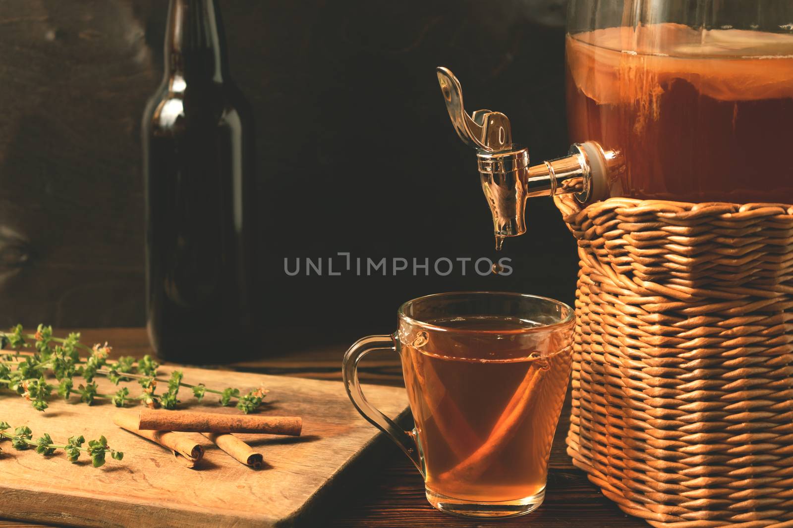 Fresh homemade Kombucha fermented tea drink in jar with faucet and in cup and bottle on black background.