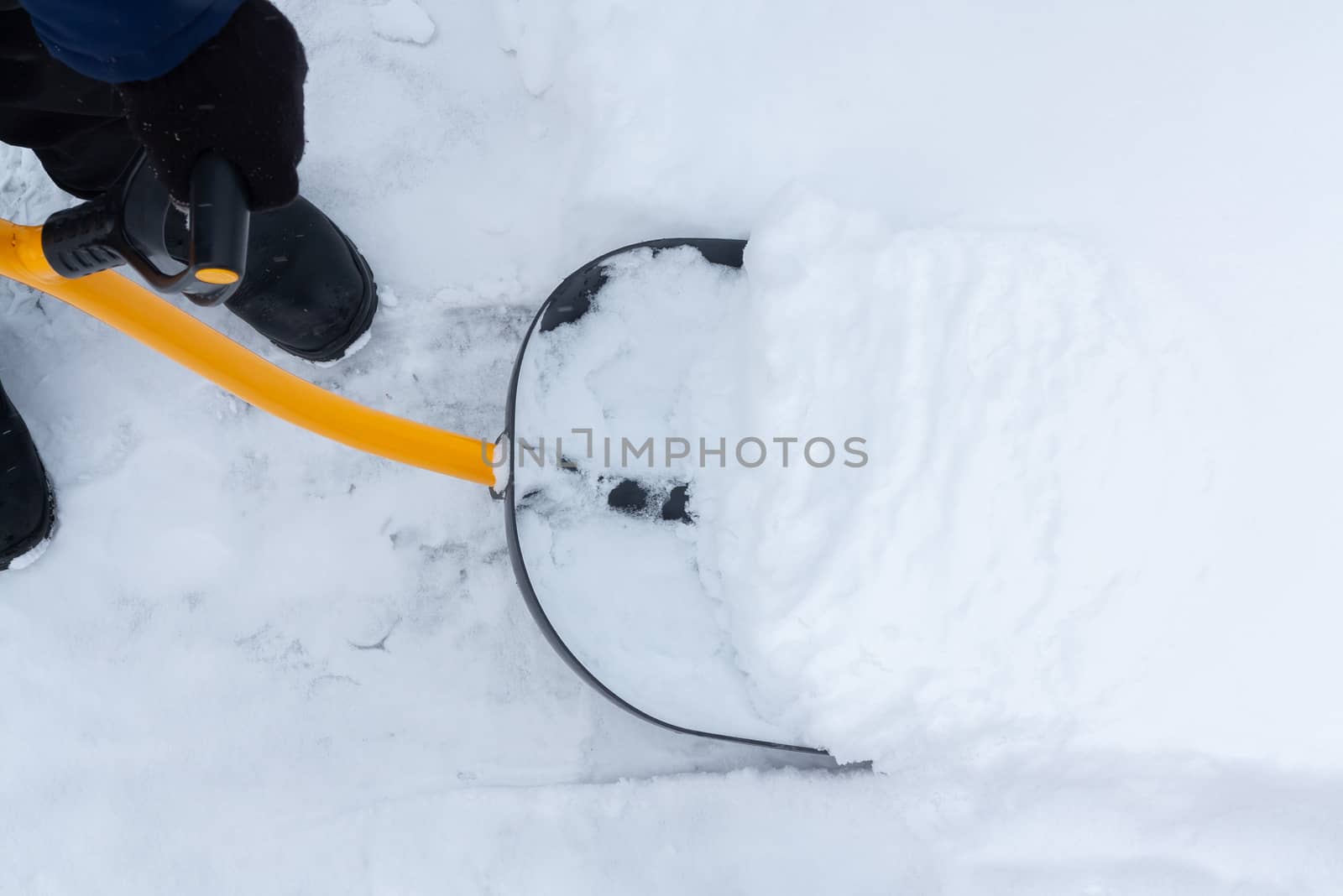 A man cleans snow in the yard with a shovel after a heavy snowfall.