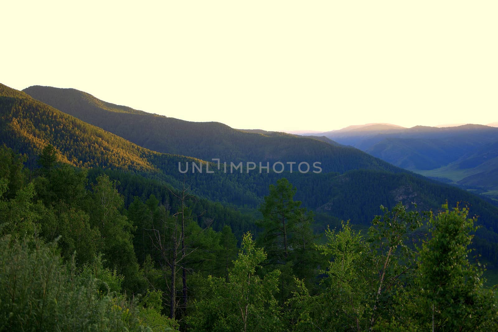 The rays of the setting sun illuminate the slopes of the mountains in orange. by alexey_zheltukhin