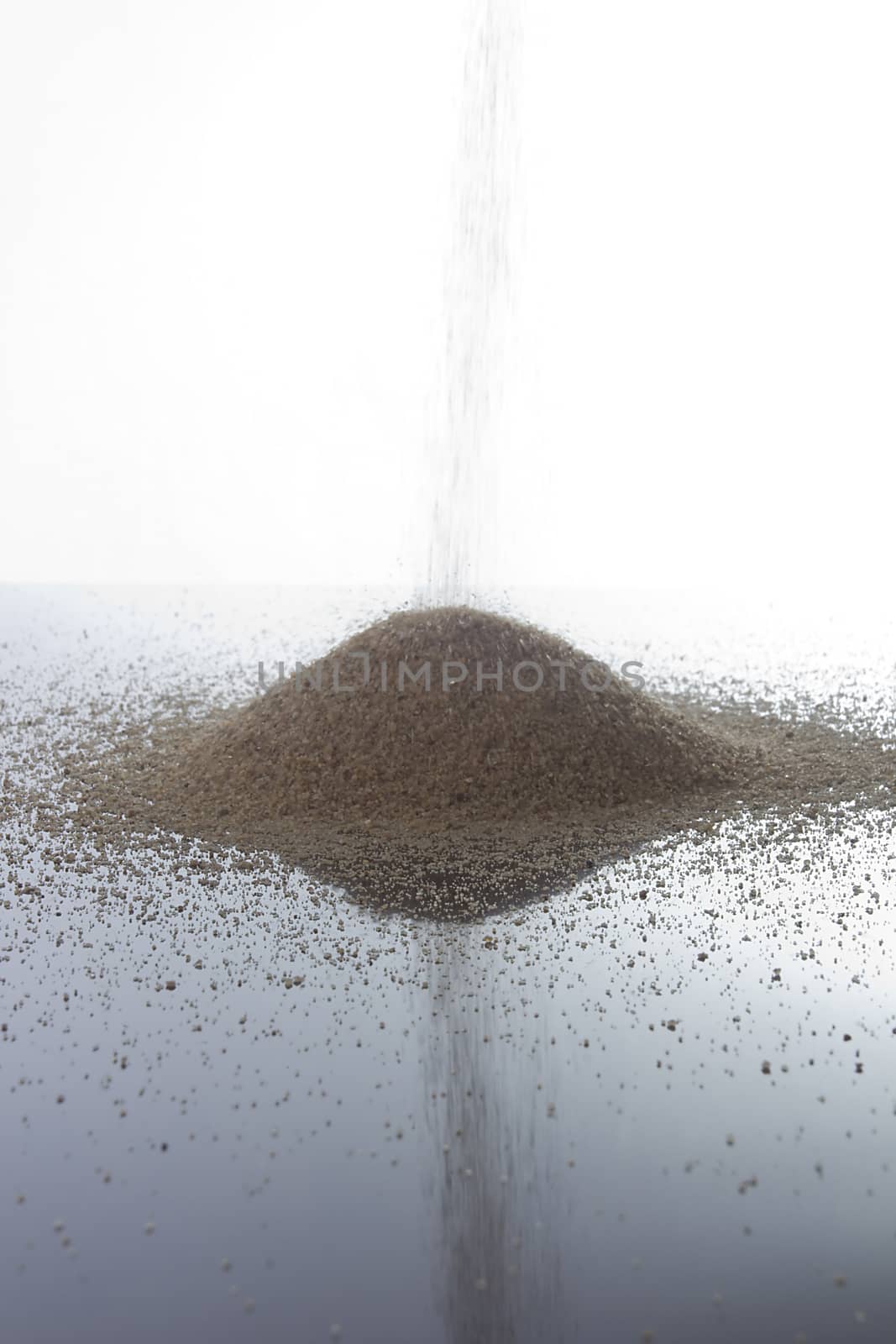Pile of sand on a white reflective surface